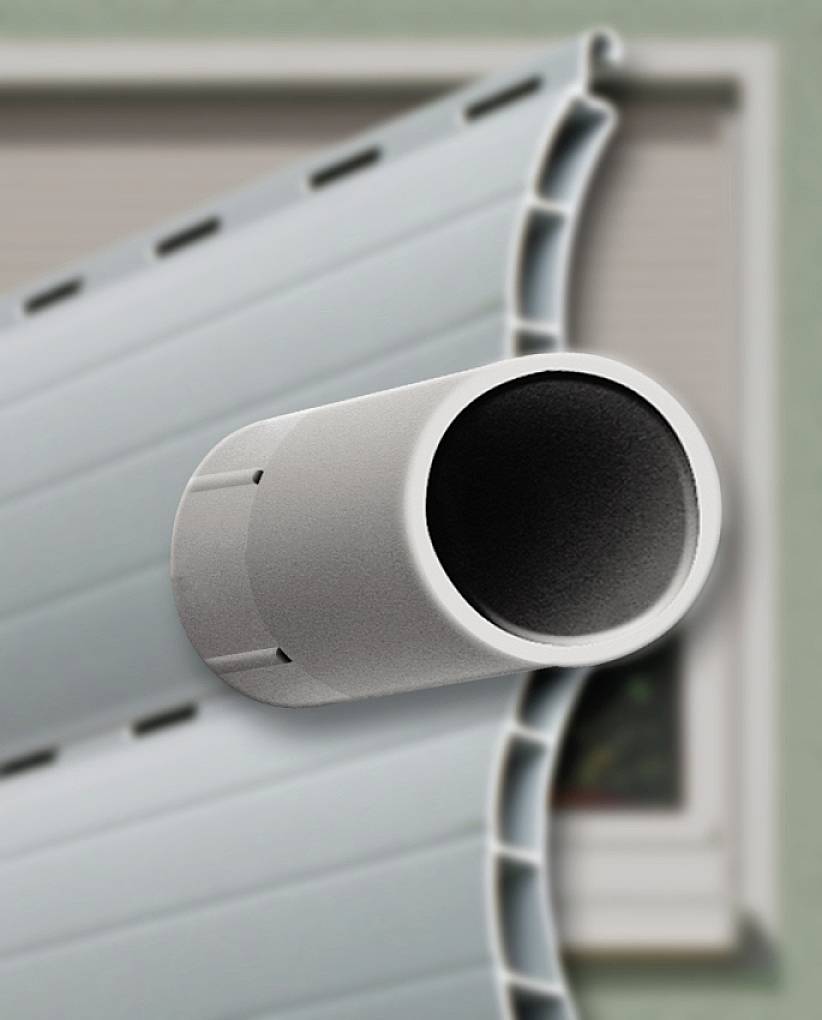 Zbliżenie rolety z okrągłą rurą prowadzoną przez listwy, w tle nieostre okno.