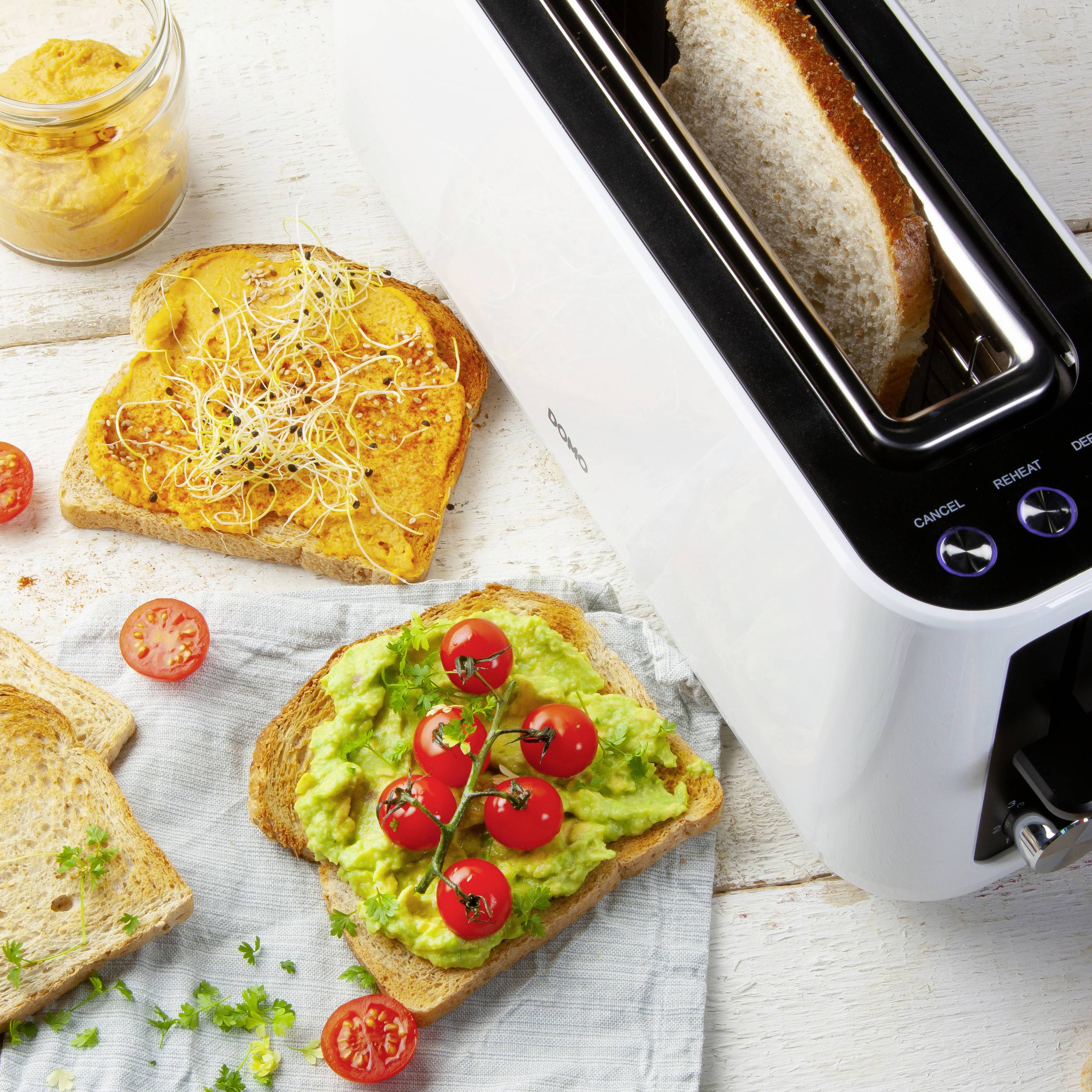 Dwie kromki tosta, jedna z awokado i pomidorami, druga z rzeżuchą. Obok toster i słoik z namazem.