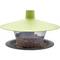 Zielony domek dla ptaków z daszkiem w kształcie pokrywy, wypełniony różnymi nasionami, umieszczony na okrągłym szarym talerzyku.