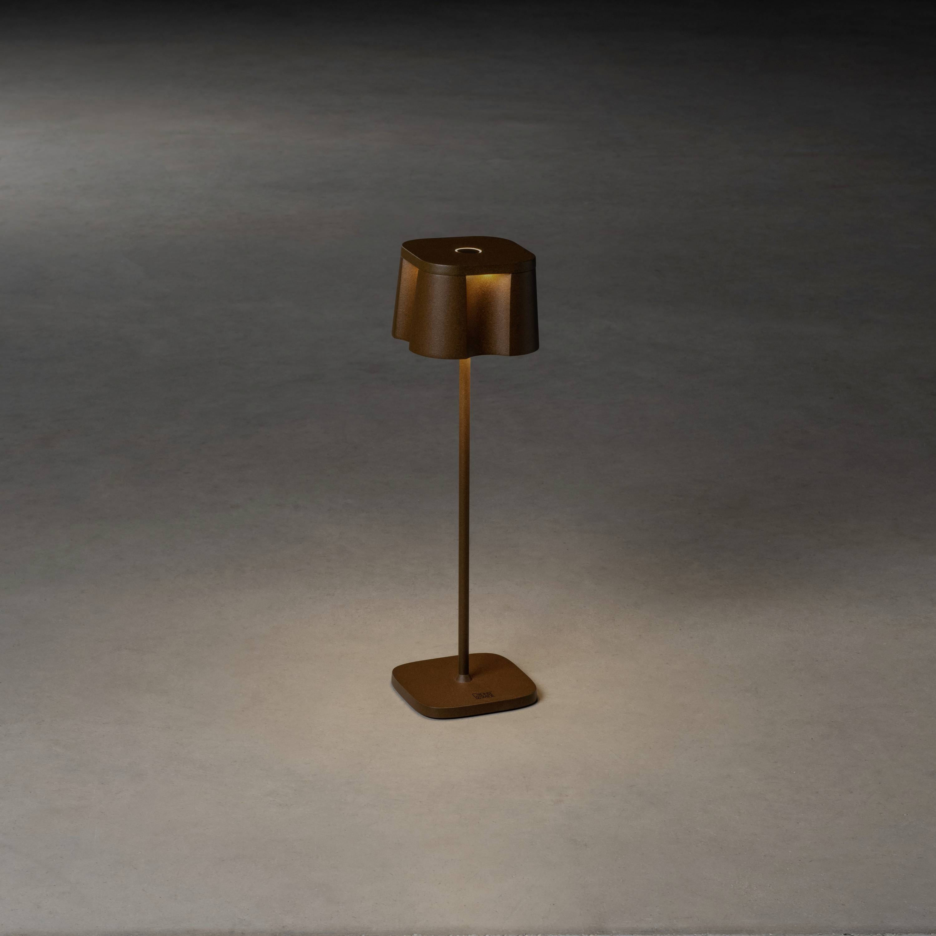 Lampa stojąca z brązowym kloszem na szarym podłożu, oświetlająca bezpośrednio obszar pod spodem.