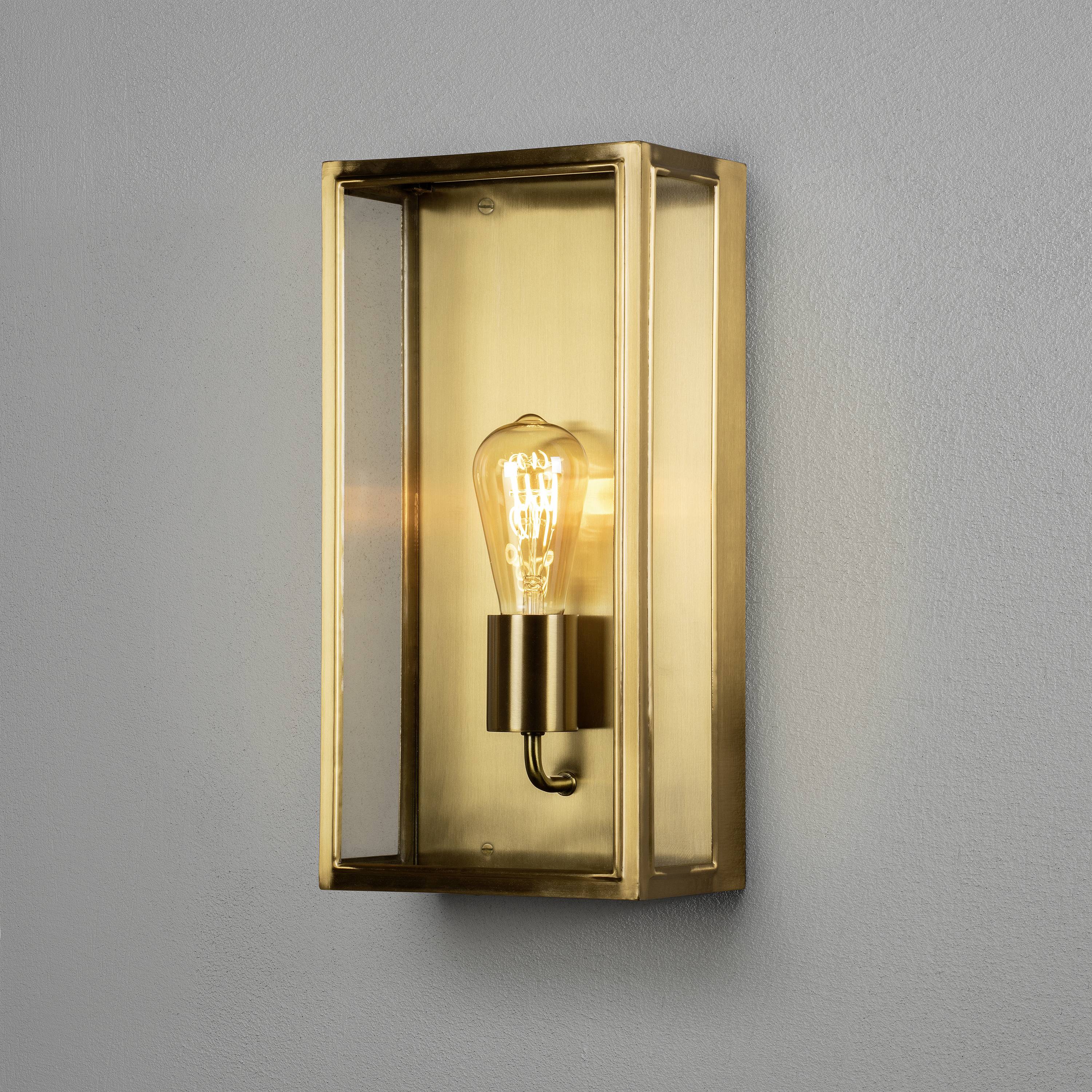 Kinkiet ze złotą, prostokątną, otwartą ramą; żarówka umieszczona centralnie w środku.