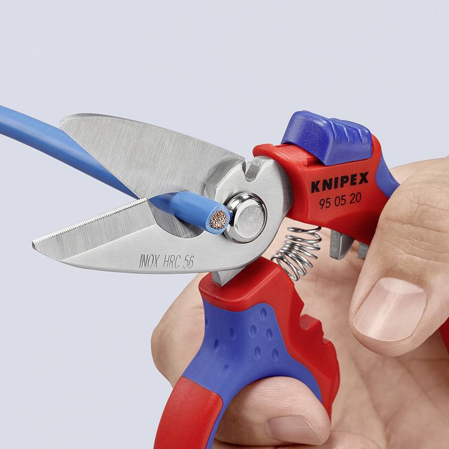 Jedna ręka trzyma obcinacz do przewodów, który ucina niebieski kabel. Na obcinaczu widnieje napis 'Knipex INOX HC 56'.
