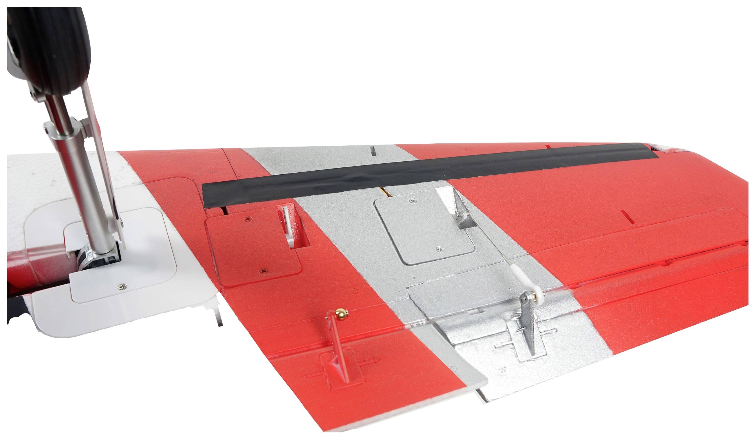 Zbliżenie fragmentu czerwono-srebrnego skrzydła samolotu z czarnymi i białymi elementami. Widoczne jest podwozie.