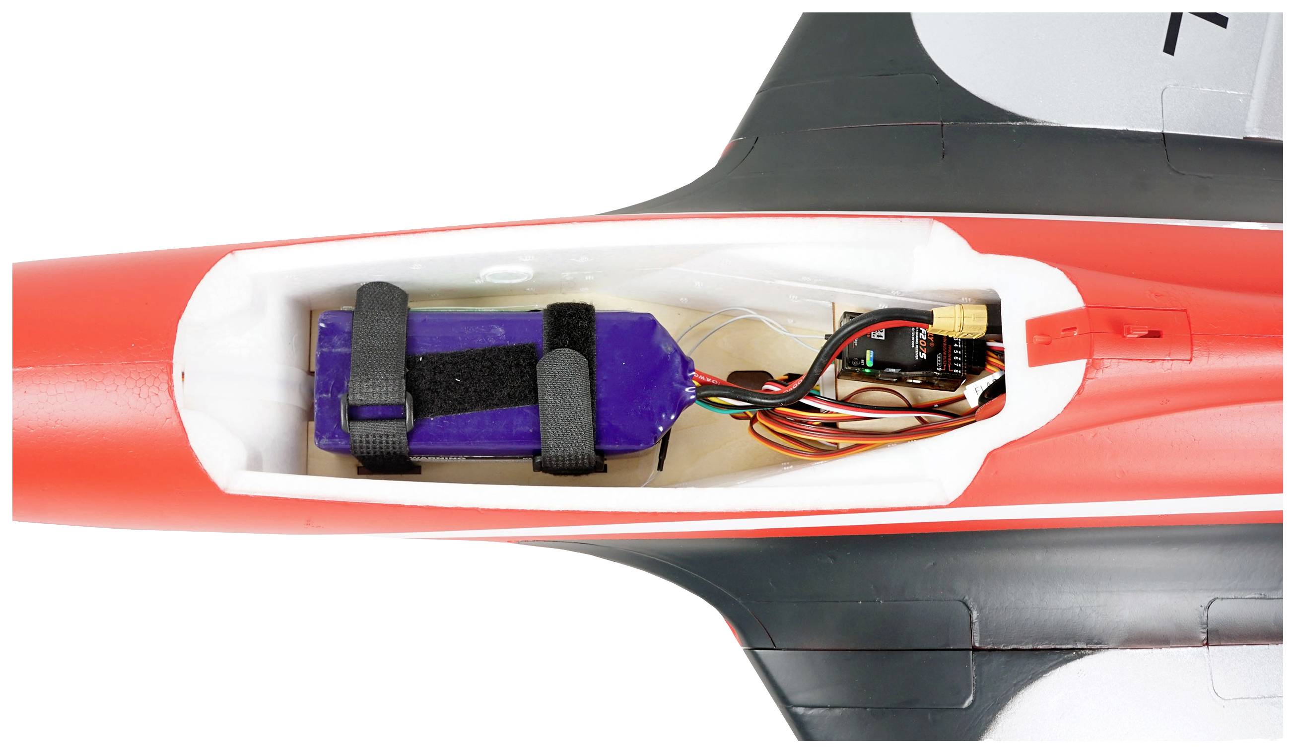 Zdalnie sterowany samolot widziany z góry z usuniętą kabiną, ukazujący wewnętrzną elektronikę i niebieską baterię.