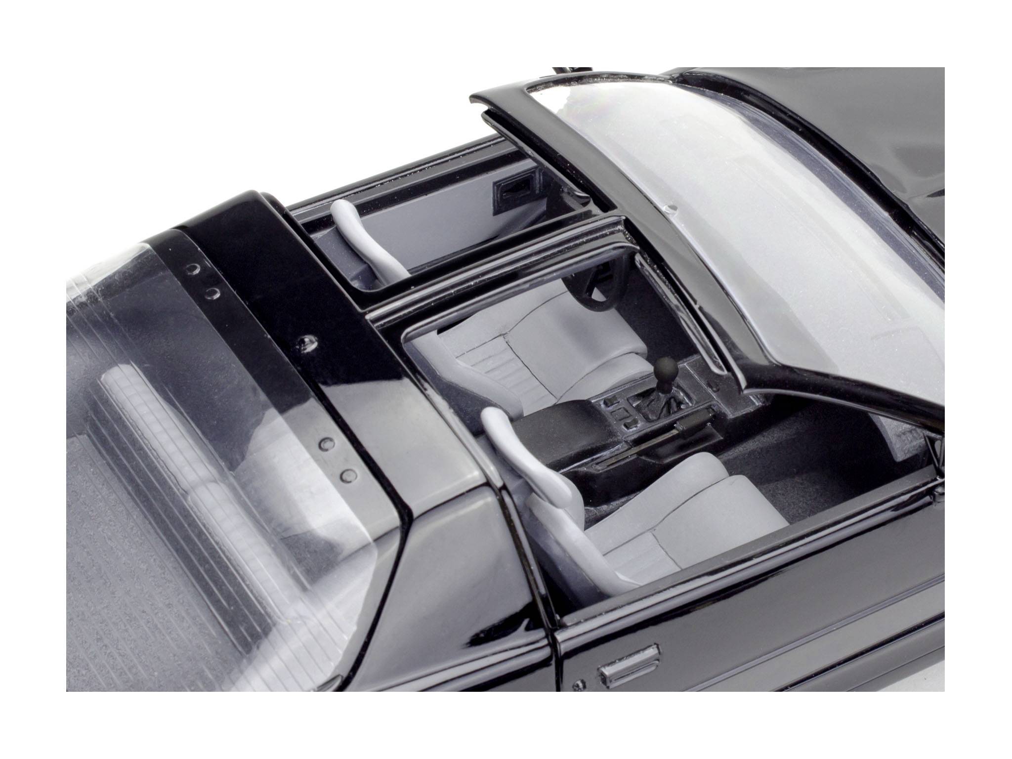 Czarny model samochodu z otwartym dachem przesuwnym, widok z góry na szare skórzane siedzenia i deskę rozdzielczą.