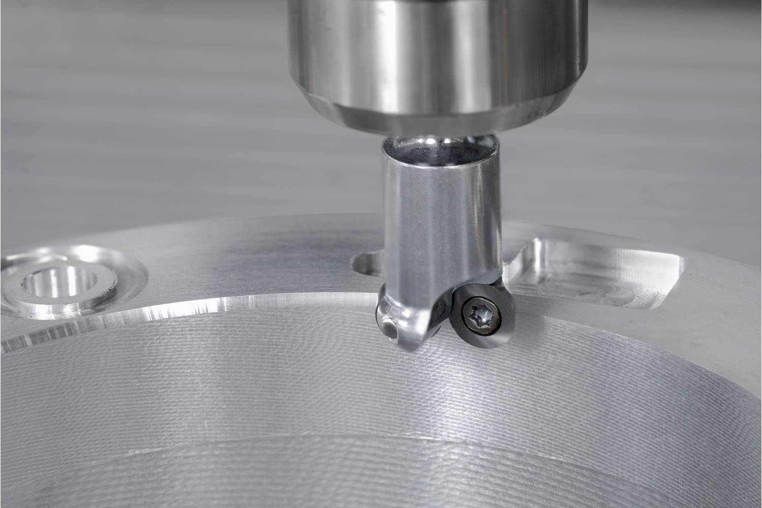 Metalowy wiertarz obrabia gładką powierzchnię metalową. Nacisk kładziony jest na precyzję narzędzia wiertniczego podczas cięcia.