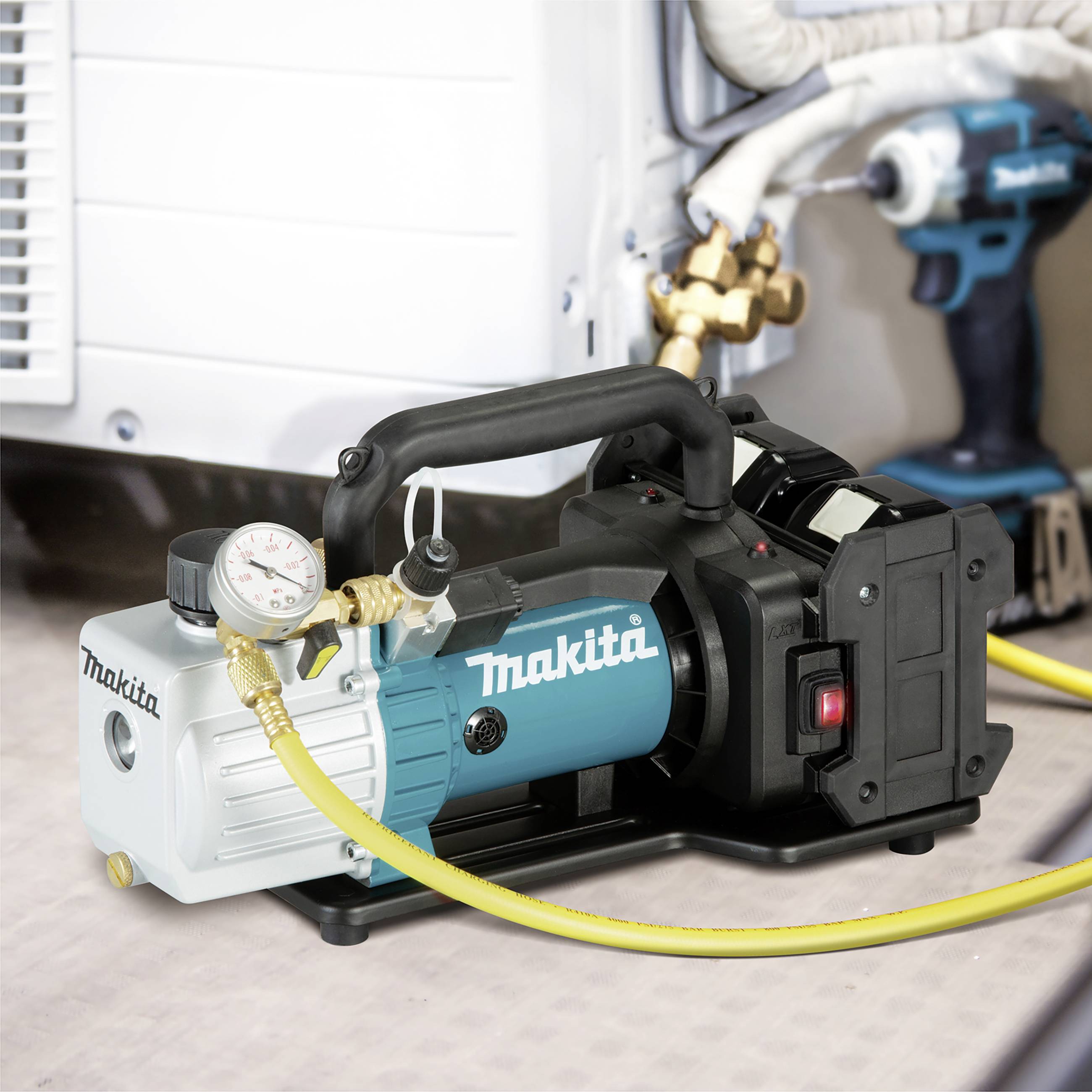 Niebiesko-biała pompa próżniowa marki 'Makita' z żółtym wężem, ustawiona przed przyłączem klimatyzacji.