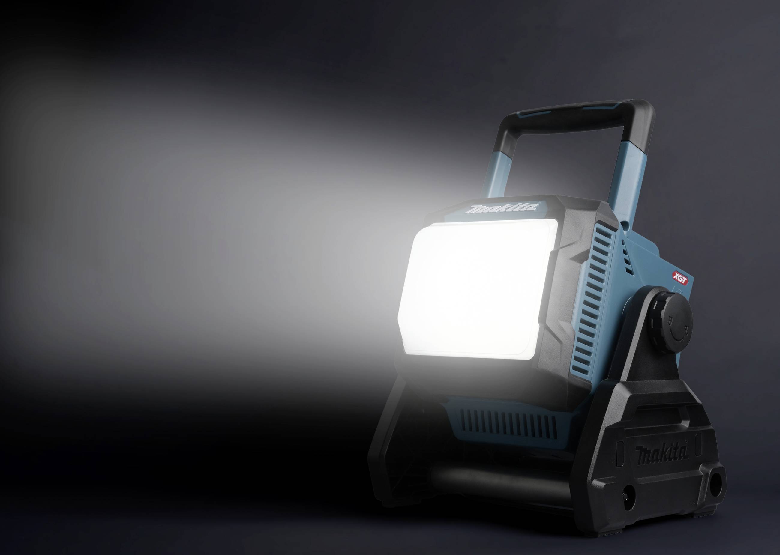 Przenośna lampa robocza emituje jasne światło w lewą stronę. Lampa jest niebiesko-czarna, z solidnym uchwytem.