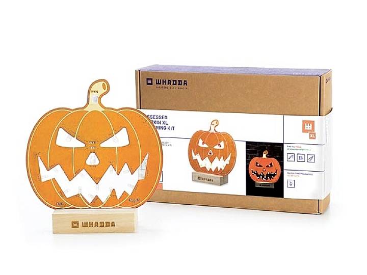 Kartonowe pudełko z zestawem do rzeźbienia dyni, przedstawiające ilustrowaną dynię z uśmiechniętą twarzą, obok której stoi podświetlana dekoracja dyniowa.