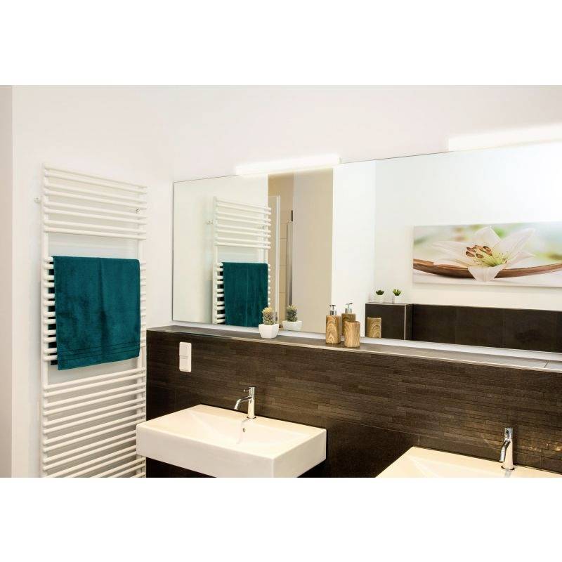 Nowoczesna łazienka z dużym lustrem, białą umywalką, ciemną drewnianą boazerią, grzejnikiem na ręczniki z zielonym ręcznikiem i dekoracją.