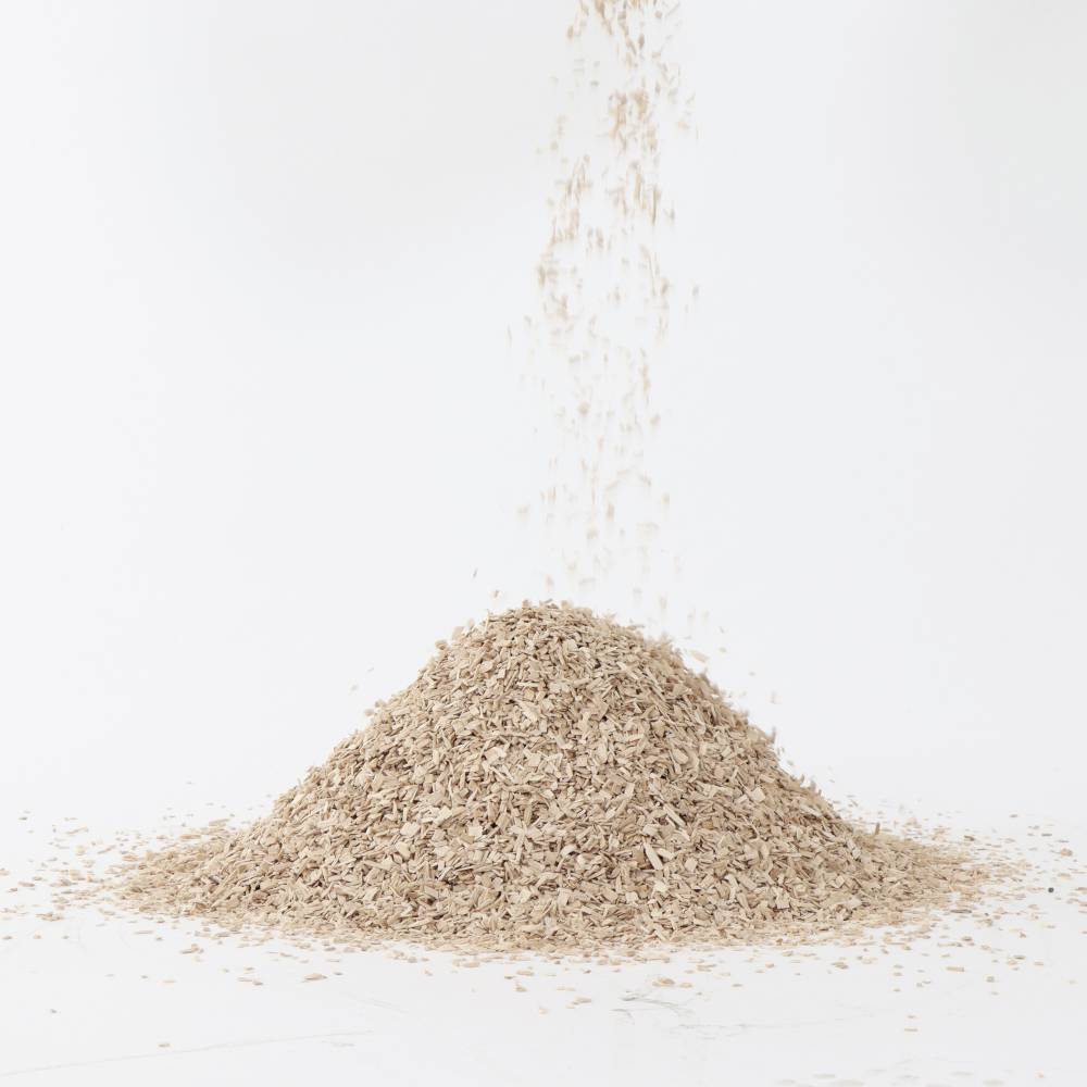 Stos trocin na białym tle, z góry spada kolejna porcja trocin.