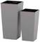 Dwa wysokie, prostokątne donice w różnych rozmiarach, wykonane z szarego materiału, ustawione obok siebie.