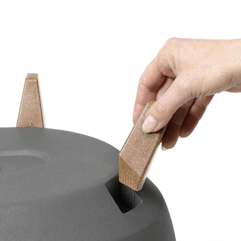 Dłoń umieszcza brązowe, wielokątne figury w szarej powierzchni z dokładnie dopasowanymi otworami.