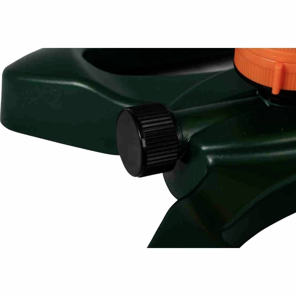 Zbliżenie plastikowego zielonego zraszacza trawnikowego z czarnym pokrętłem regulacyjnym i pomarańczowym dyszem.