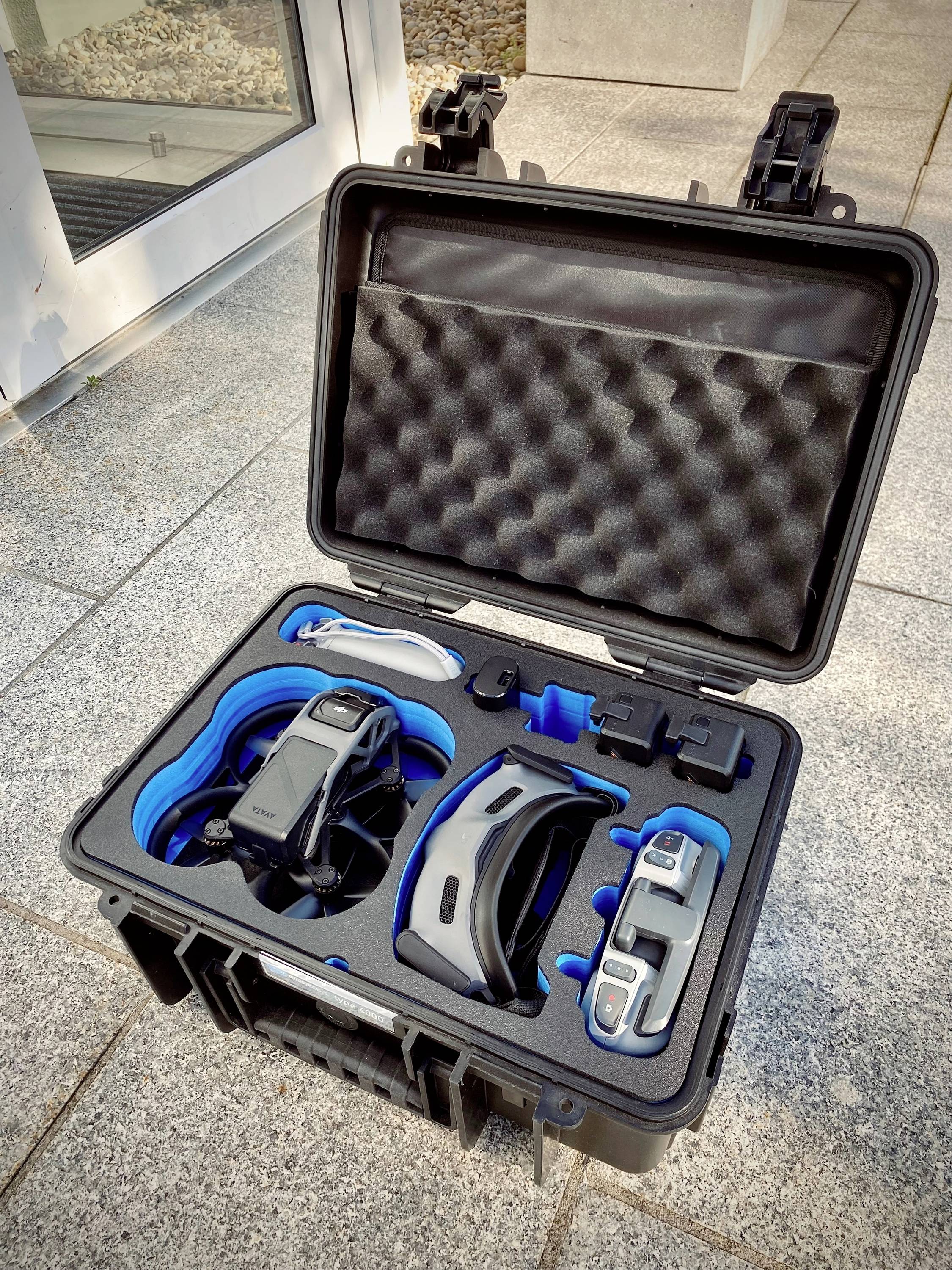 Piankowe etui z dronem, kontrolerem i akcesoriami, starannie ułożonymi w dokładnie dopasowanych wycięciach.