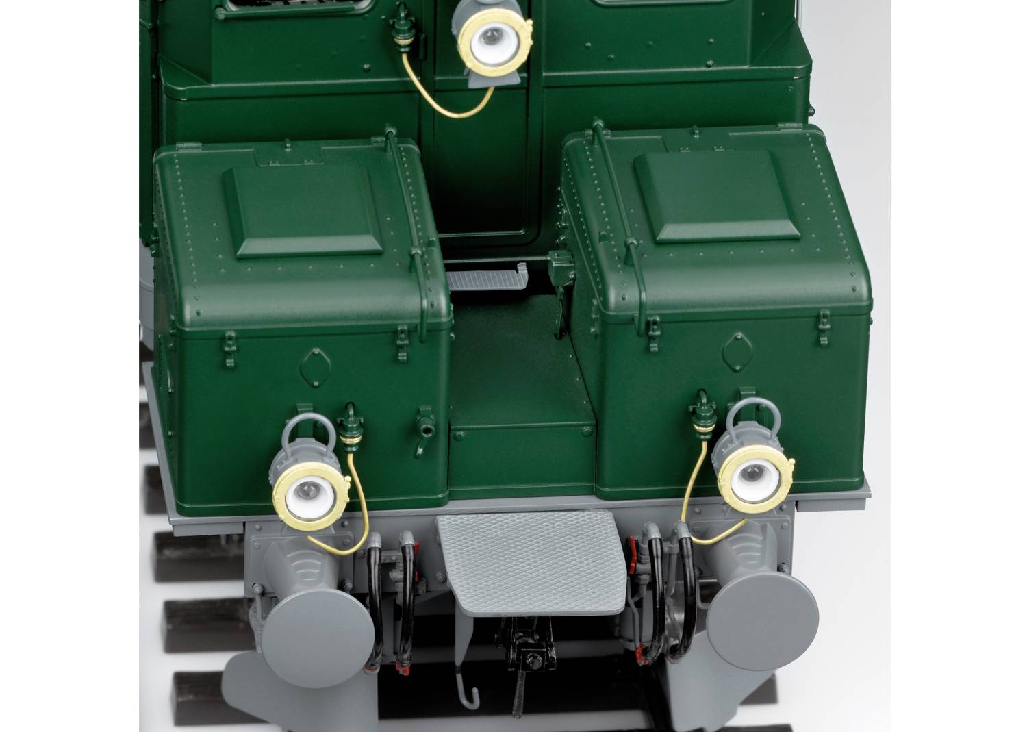 Zielony zabytkowy pojazd szynowy z dwoma reflektorami z przodu i wyposażeniem technicznym, sfotografowany z bliska od przodu.