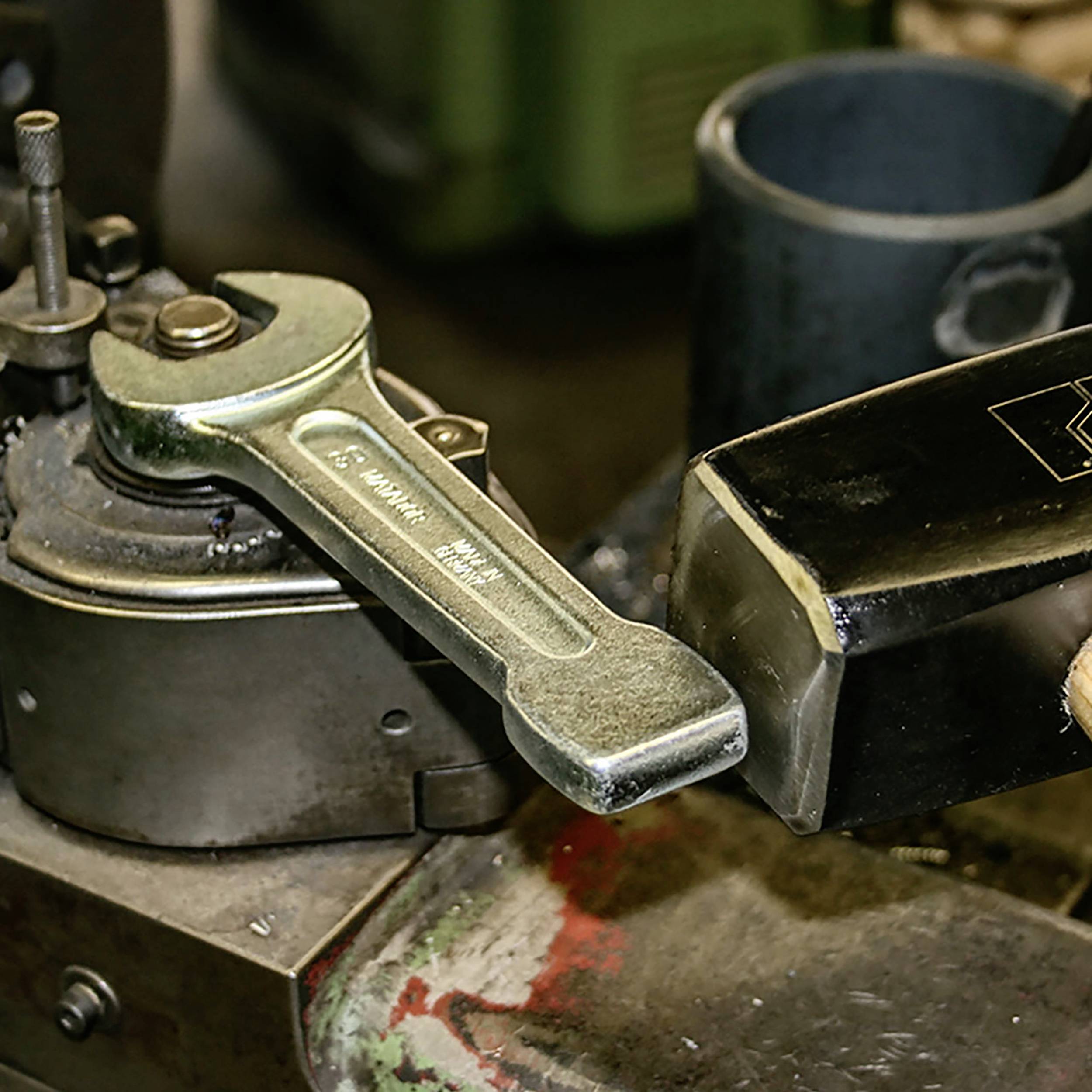 Średni komponent maszynowy jest obrabiany kluczem nasadowym. Fokus jest skierowany na narzędzie i proces roboczy.