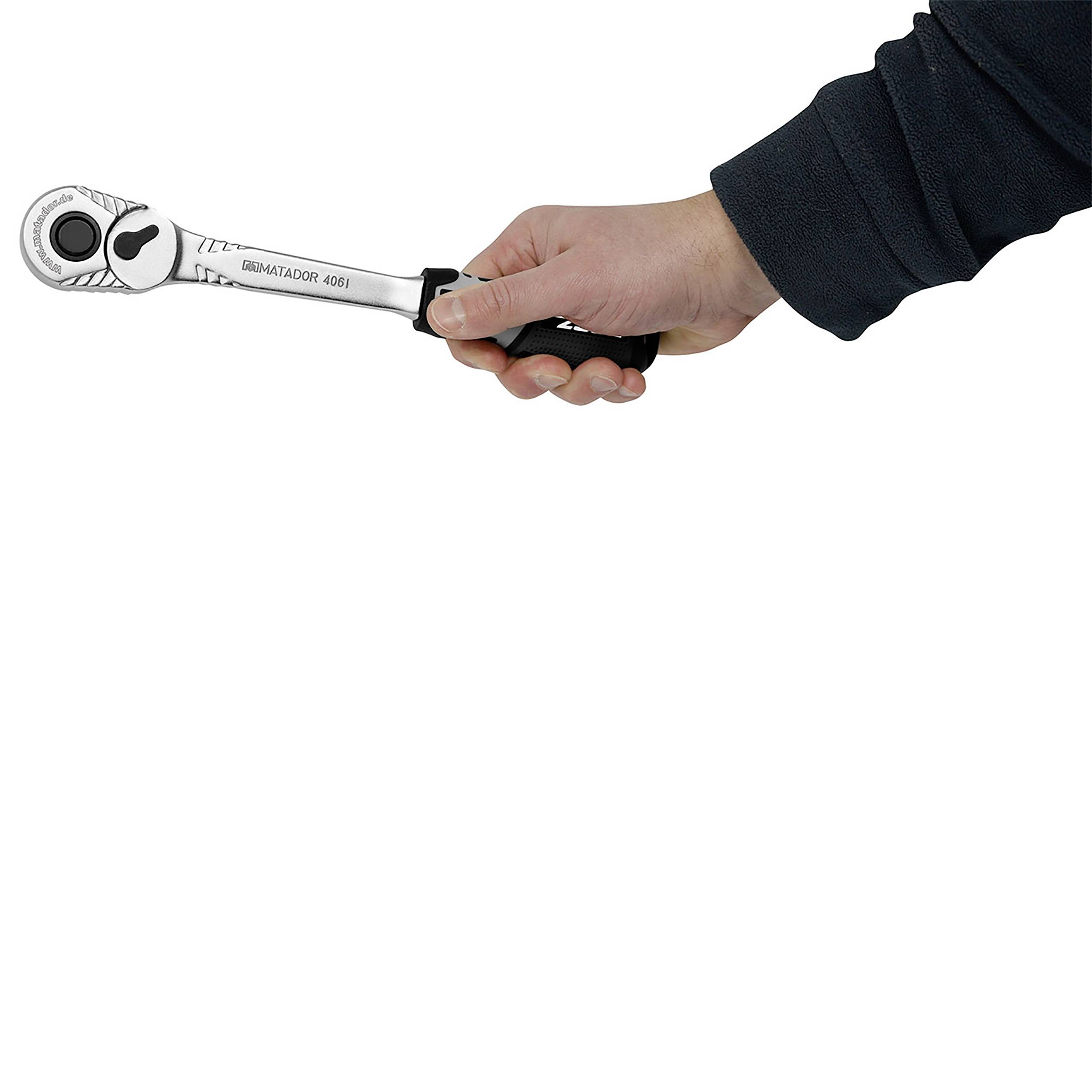 Jedna ręka trzyma srebrny klucz dynamometryczny ustawiony w pozycji poziomej.