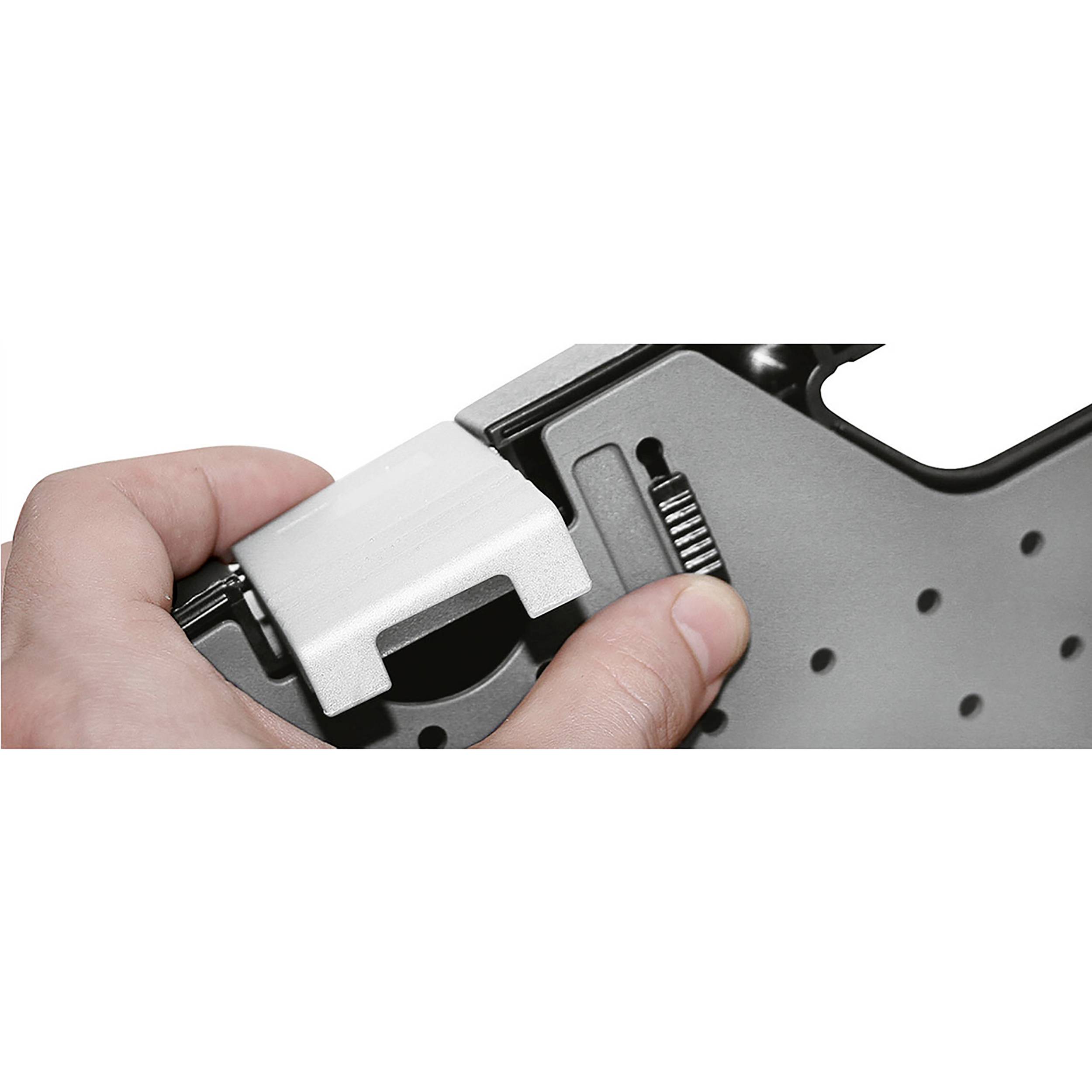 Dłoń trzyma szary przedmiot z mechanizmem regulacyjnym i śrubą.