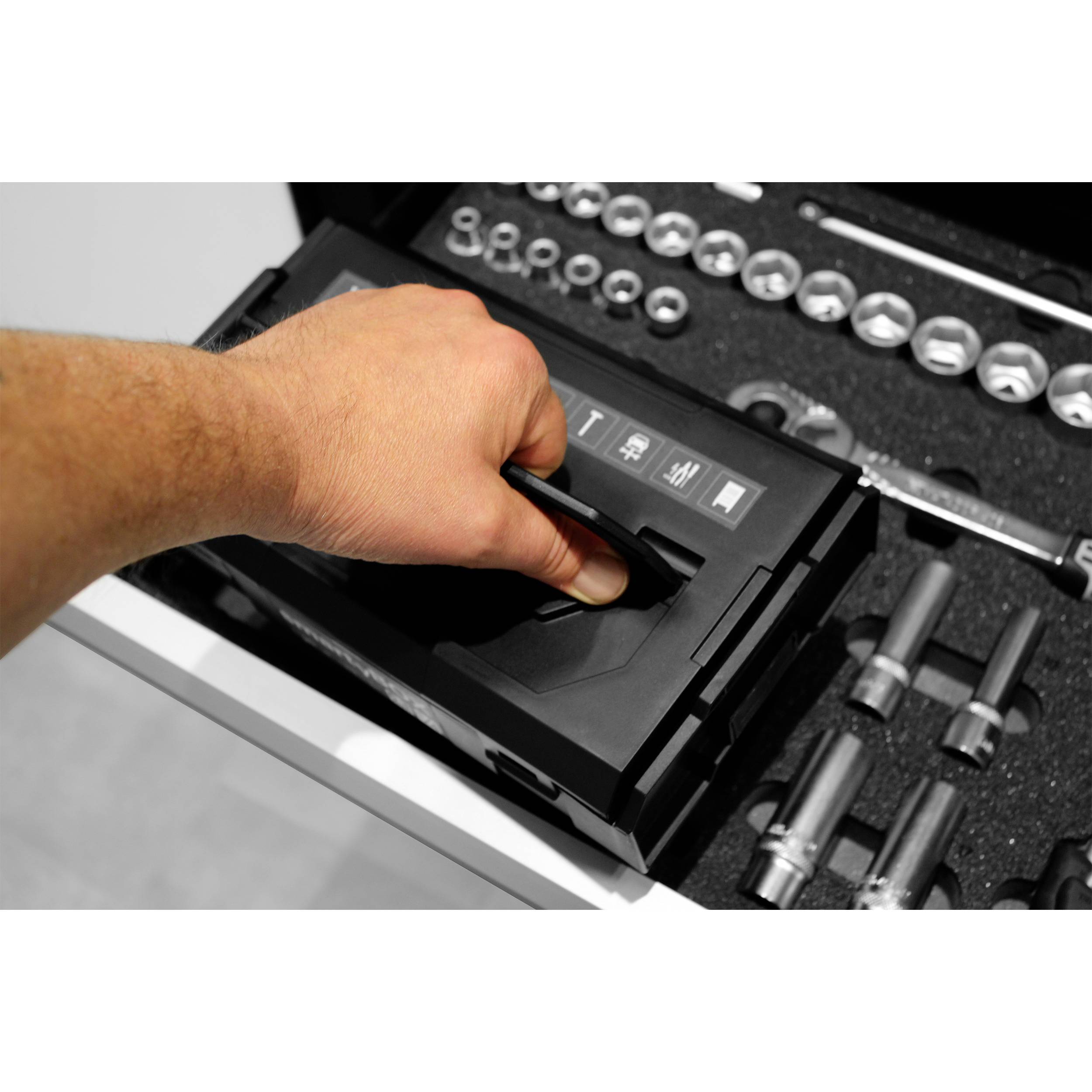 Dłoń otwiera skrzynkę narzędziową z posortowanymi narzędziami i kluczami nasadowymi.