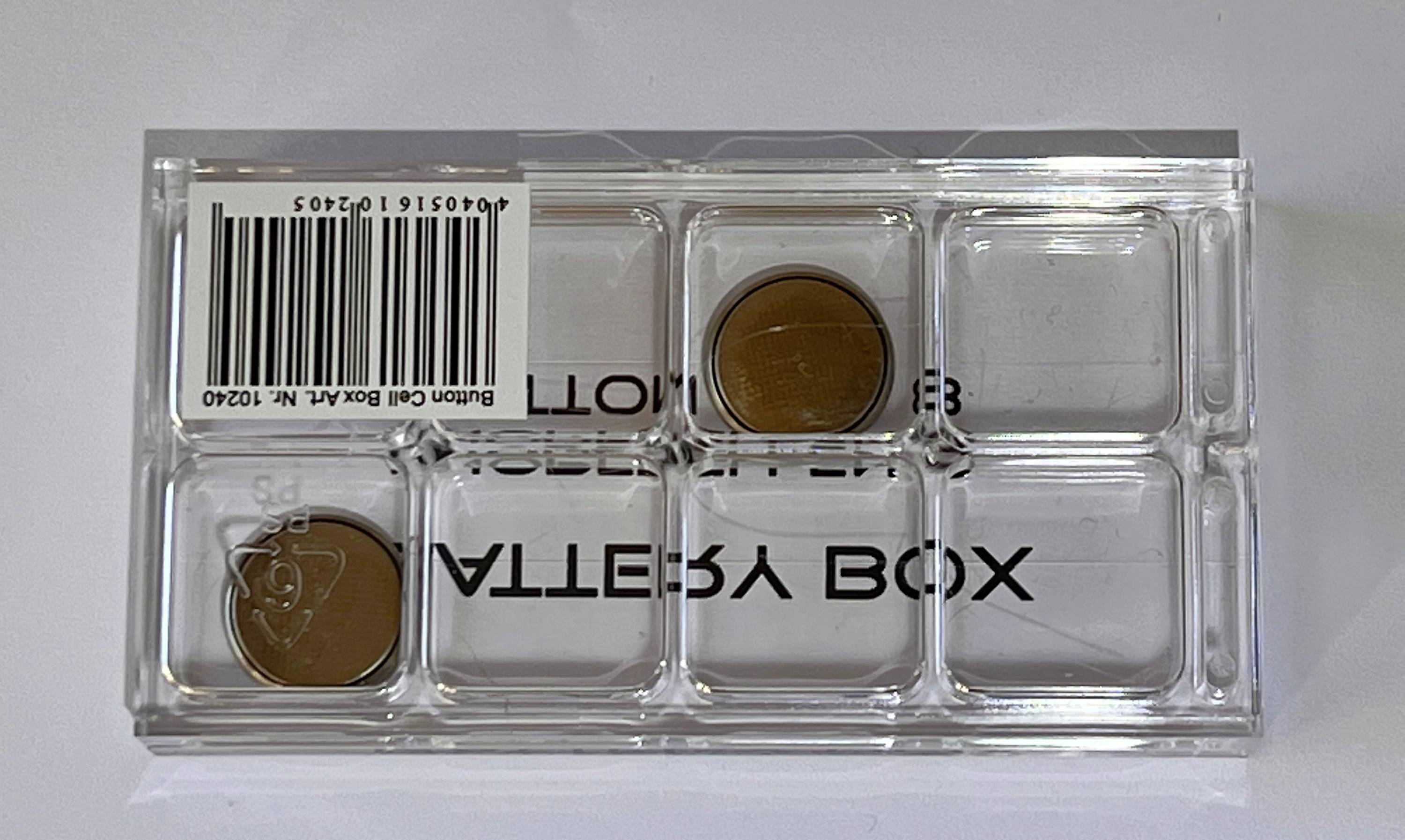 Plastikowe pudełko z dwoma monetami, jedna z widocznym herbem. Kod kreskowy i napis 'MÜNZBOX' na pudełku.