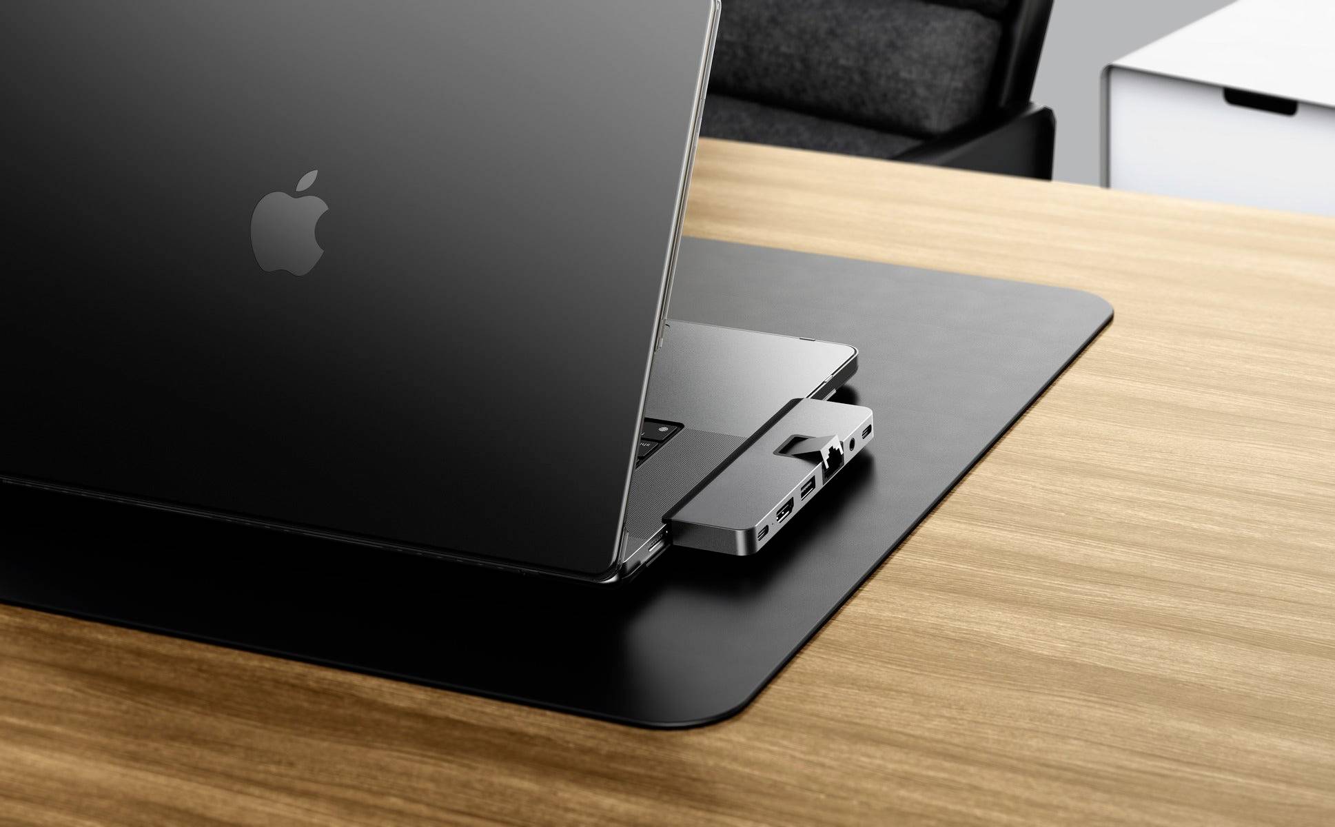 Laptop z hubem USB jest umieszczony na drewnianym biurku. Hub oferuje wiele możliwości podłączenia urządzeń.