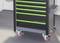 Wózek narzędziowy na kółkach z pięcioma zielonymi uchwytami w szufladach, stojący na szarej podłodze.