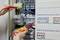 Osoba sprawdza połączenia elektryczne multimetrem w otwartej szafce rozdzielczej pełnej przewodów i bezpieczników.