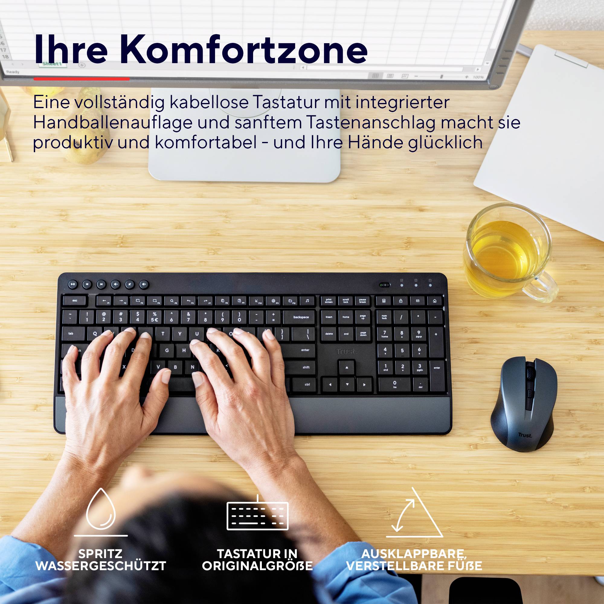 Mężczyzna pisze na klawiaturze z odejmowalną podpórką pod nadgarstek, obok mysz i napój na biurku. Tekst u góry: 'Twoja strefa komfortu'.