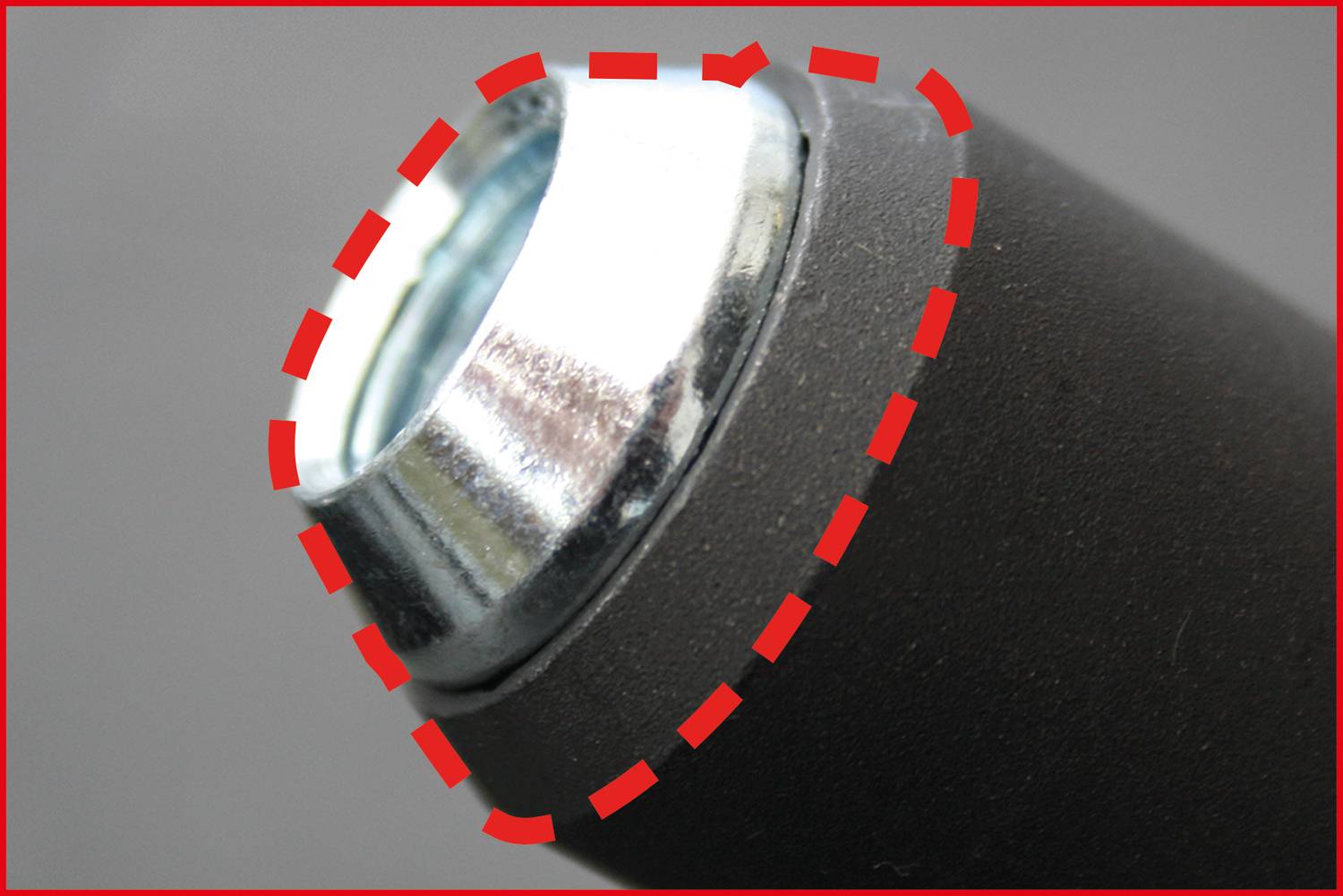 Zbliżenie metalowego, cylindrycznego obiektu z odblaskowym końcem, obramowanego przerywaną czerwoną linią.