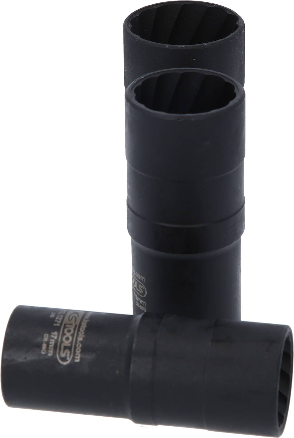 Trzy czarne metalowe nakrętki, dwie stoją pionowo, a jedna leży poprzecznie przed nimi. Mają prążkowane wnętrza.