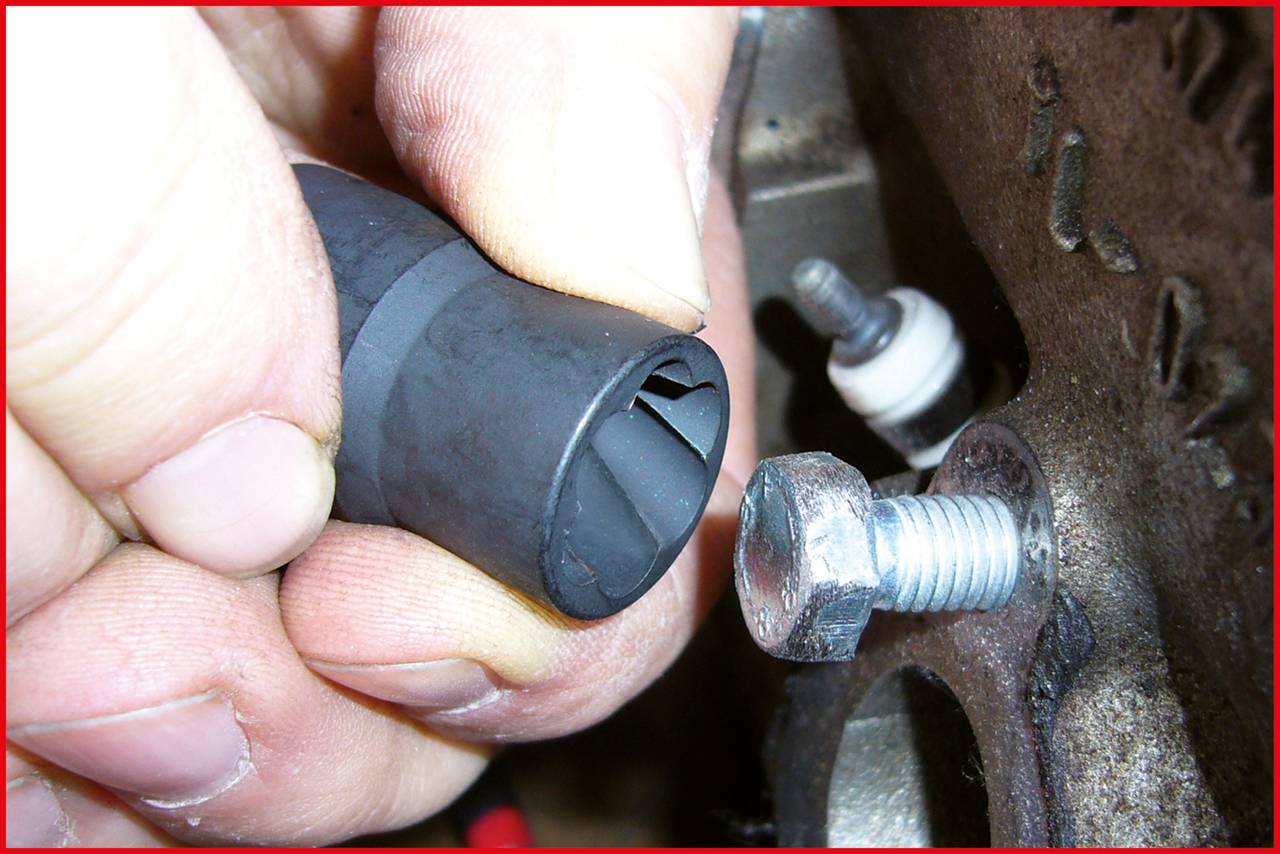 Zbliżenie dłoni trzymających gumowy korek obok metalowej śruby. Śruba umieszczona w mechanicznie obrabiany element metalowy.