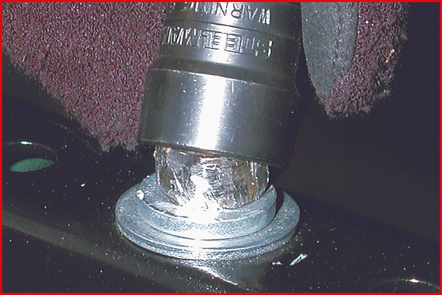 Zabezpieczenie przed przekręceniem nakrętki z uszkodzoną główką śruby i zamontowaną gumową osłoną ochronną.