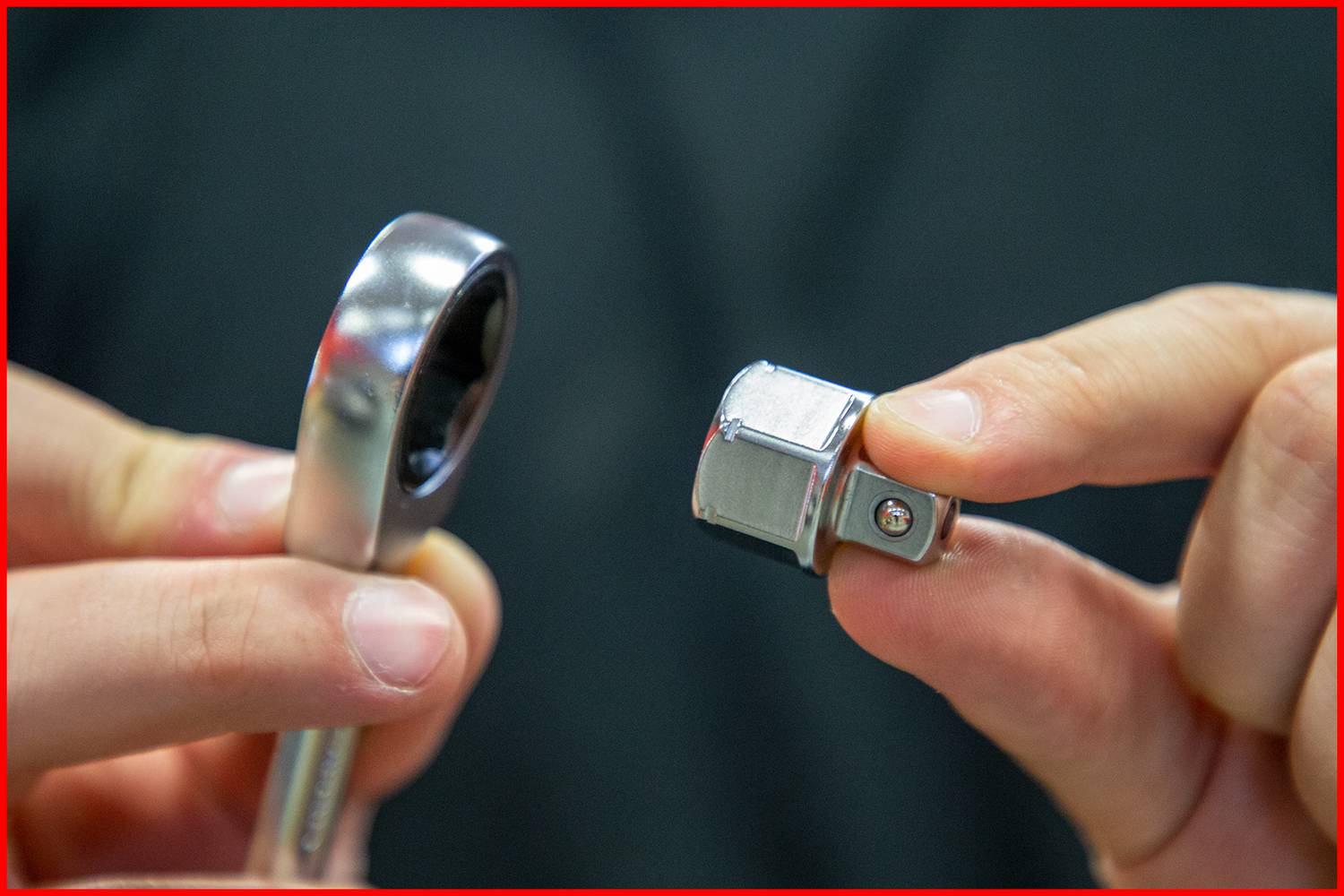 Osoba trzyma klucz nasadowy i nasadkę. Fokus jest skierowany na elementy narzędzi, aby zilustrować ich zastosowanie lub funkcję.