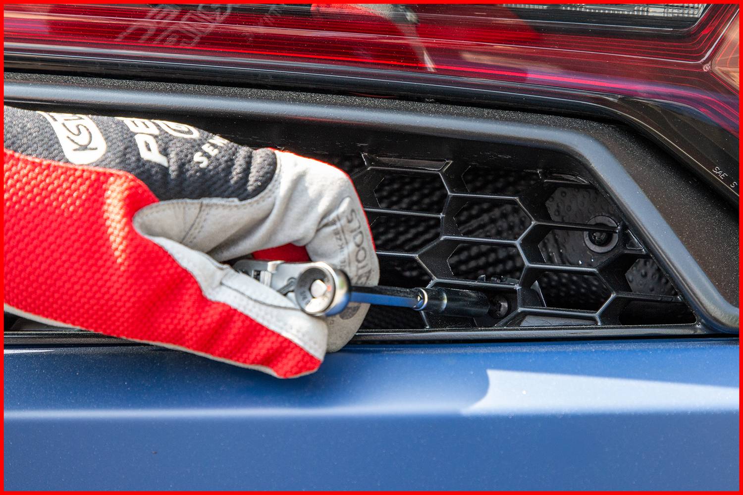 Dłoń w rękawicy odkręca wkrętakiem śrubę w plastrowatej strukturze kratownicy samochodowej.