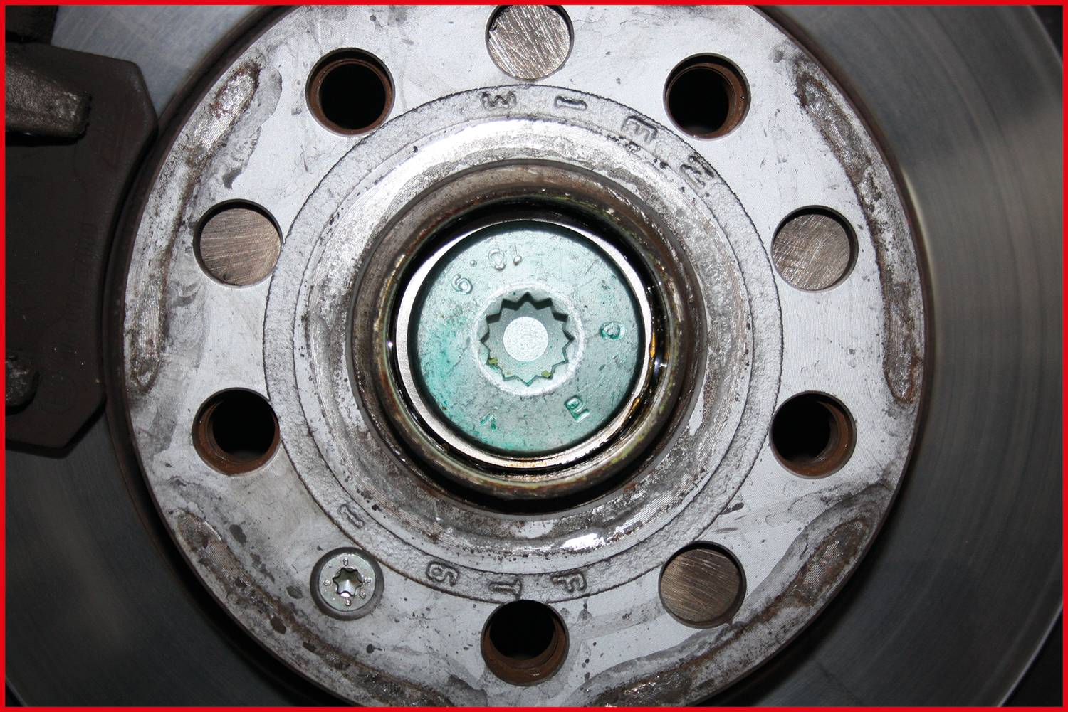 Zbliżenie układu hamulcowego samochodu, ukazujące zacisk hamulcowy i tarczę hamulcową. Złożona struktura podkreśla szczegóły mechaniczne.