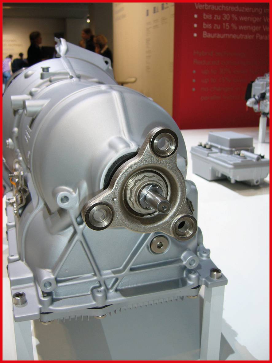 Metalowe przekładnie na wystawie z technicznym tłem i plakatem informacyjnym w tle.