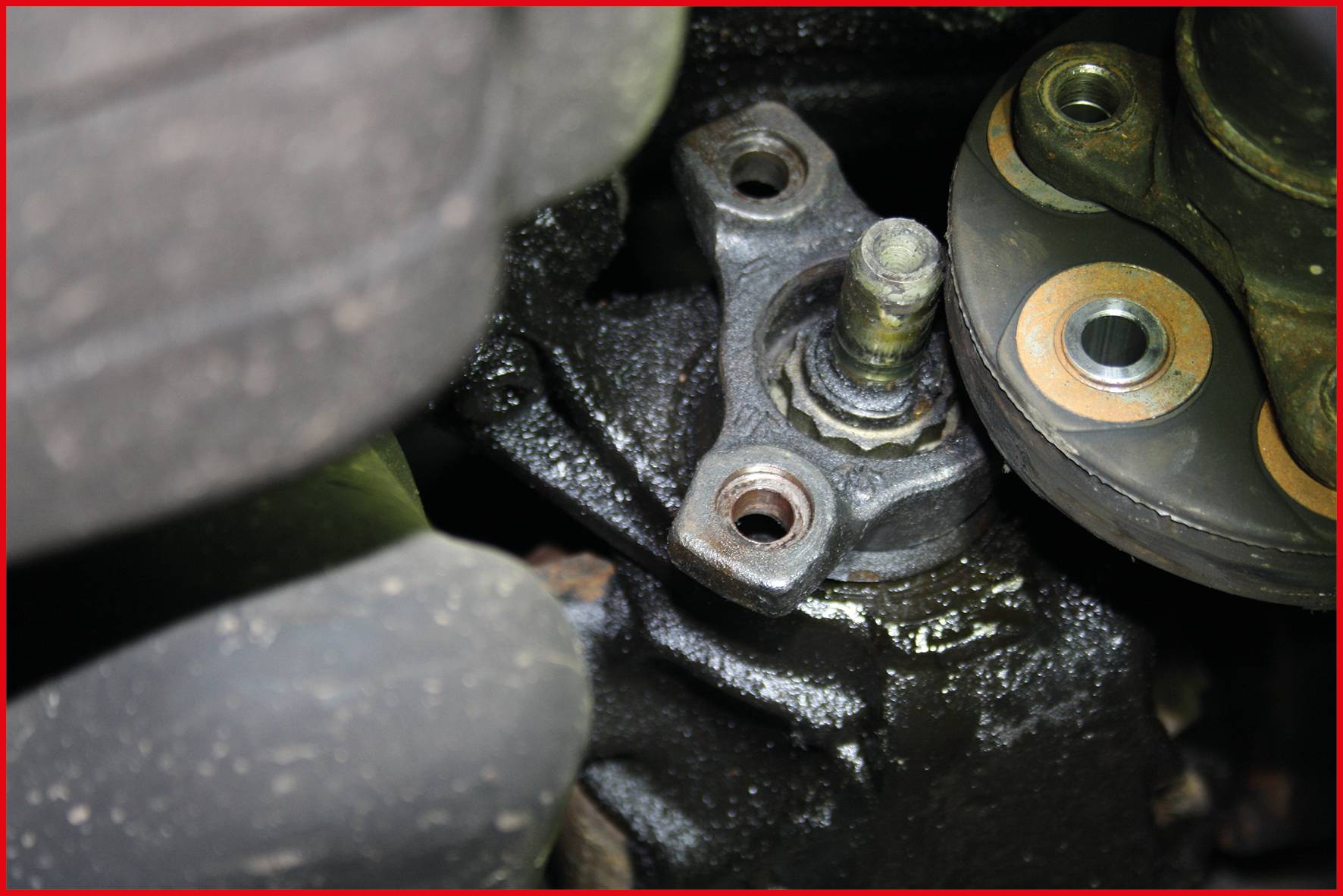 Zbliżenie elementu samochodowego, prawdopodobnie fragmentu zawieszenia lub układu kierowniczego, ukazuje śruby i metalowe części z widocznymi oznakami zużycia.