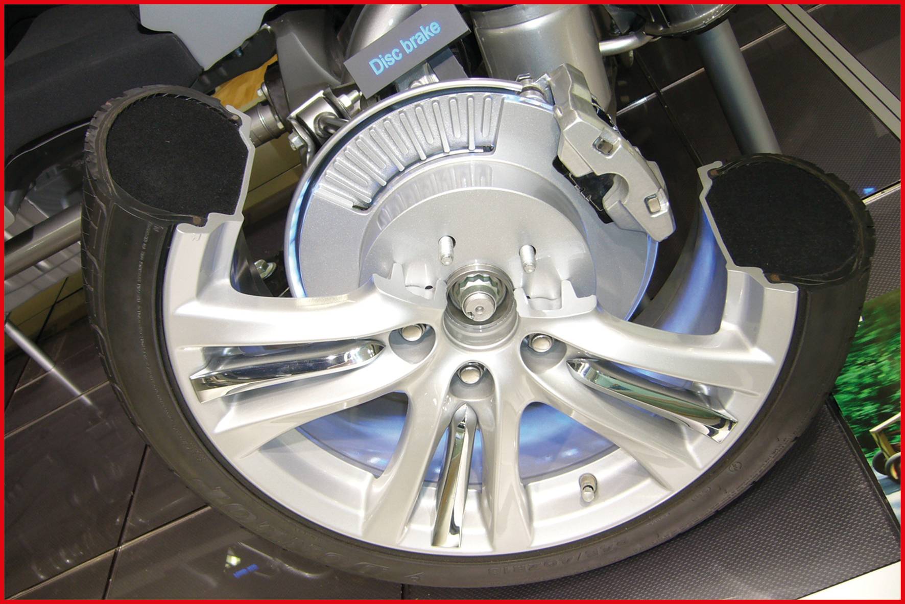 Przekrój poprzeczny opony samochodu ukazuje wewnętrzną tarczę hamulcową oraz obręcz.