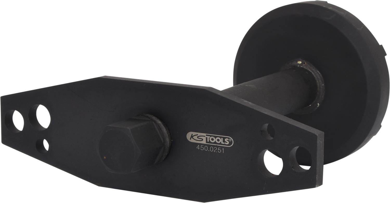 Czarna część narzędzia firmy KS Tools, o kształcie cylindrycznym, z nakrętką sześciokątną pośrodku i kilkoma otworami mocującymi.