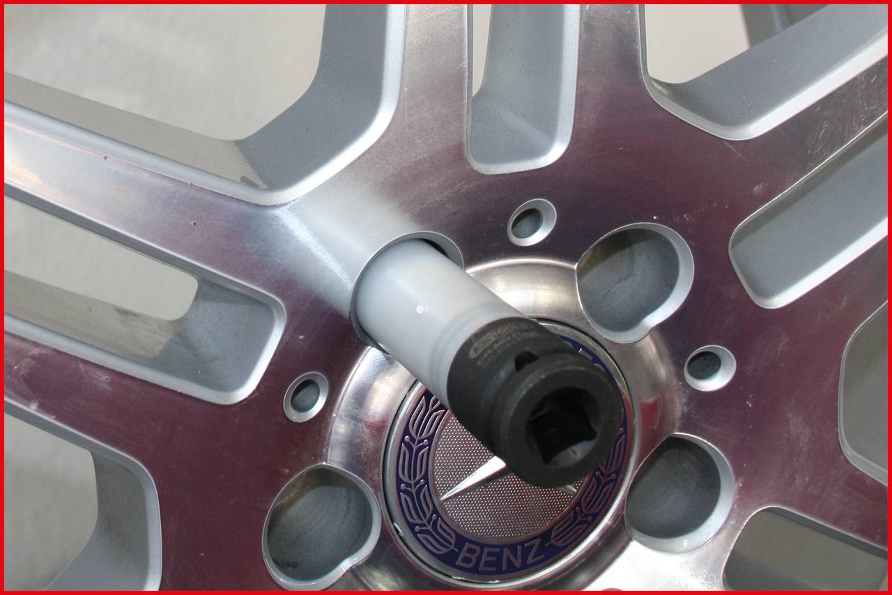 Zbliżenie felgi samochodowej z srebrnymi szprychami. Klucz do nakrętek jest umieszczony pośrodku, gotowy do demontażu.