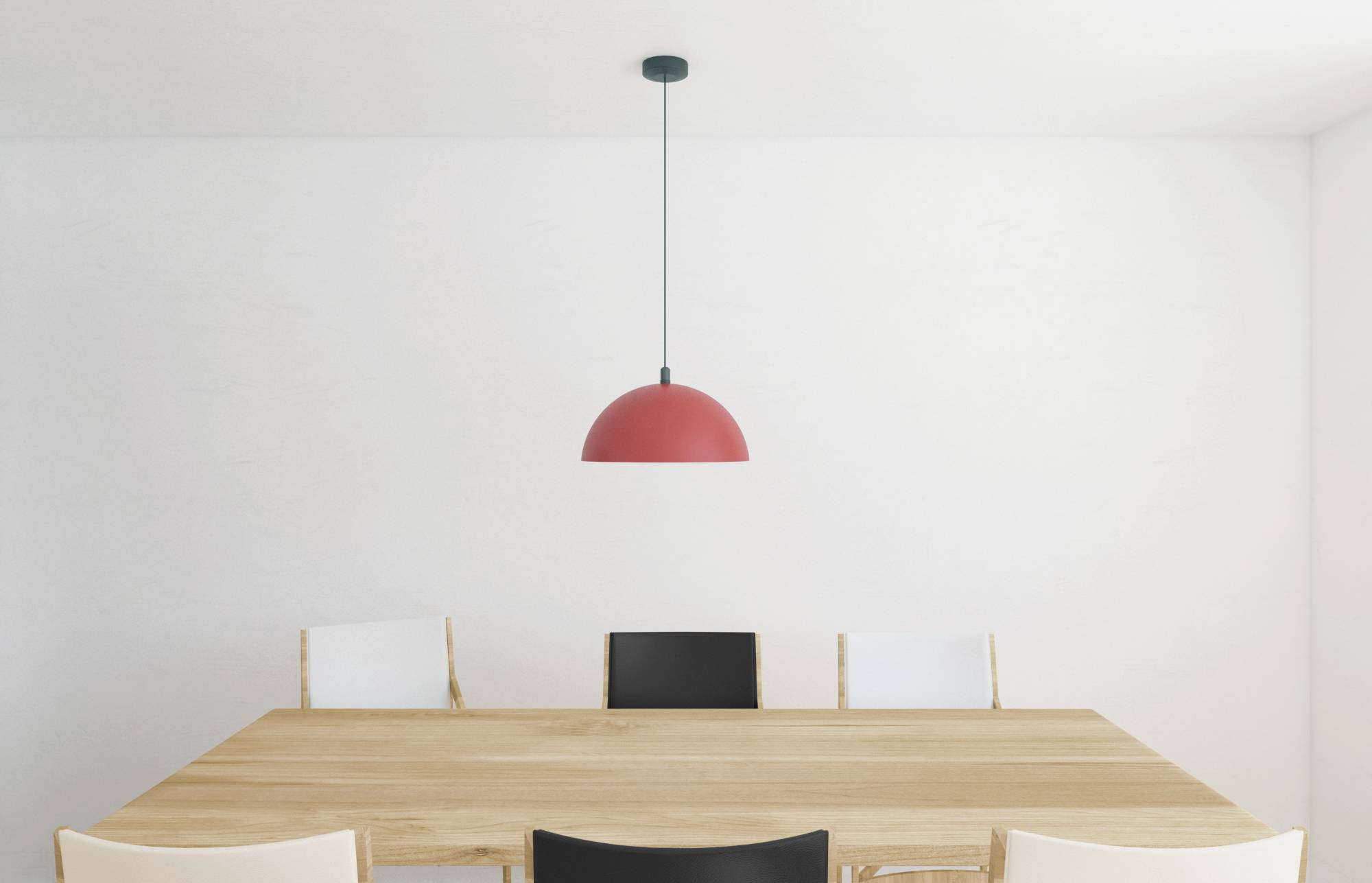 Minimalistyczne wnętrze z drewnianym stołem jadalnianym, otoczonym dwoma białymi i dwoma czarnymi krzesłami. Czerwona lampa wisząca zawieszona jest centralnie nad stołem.