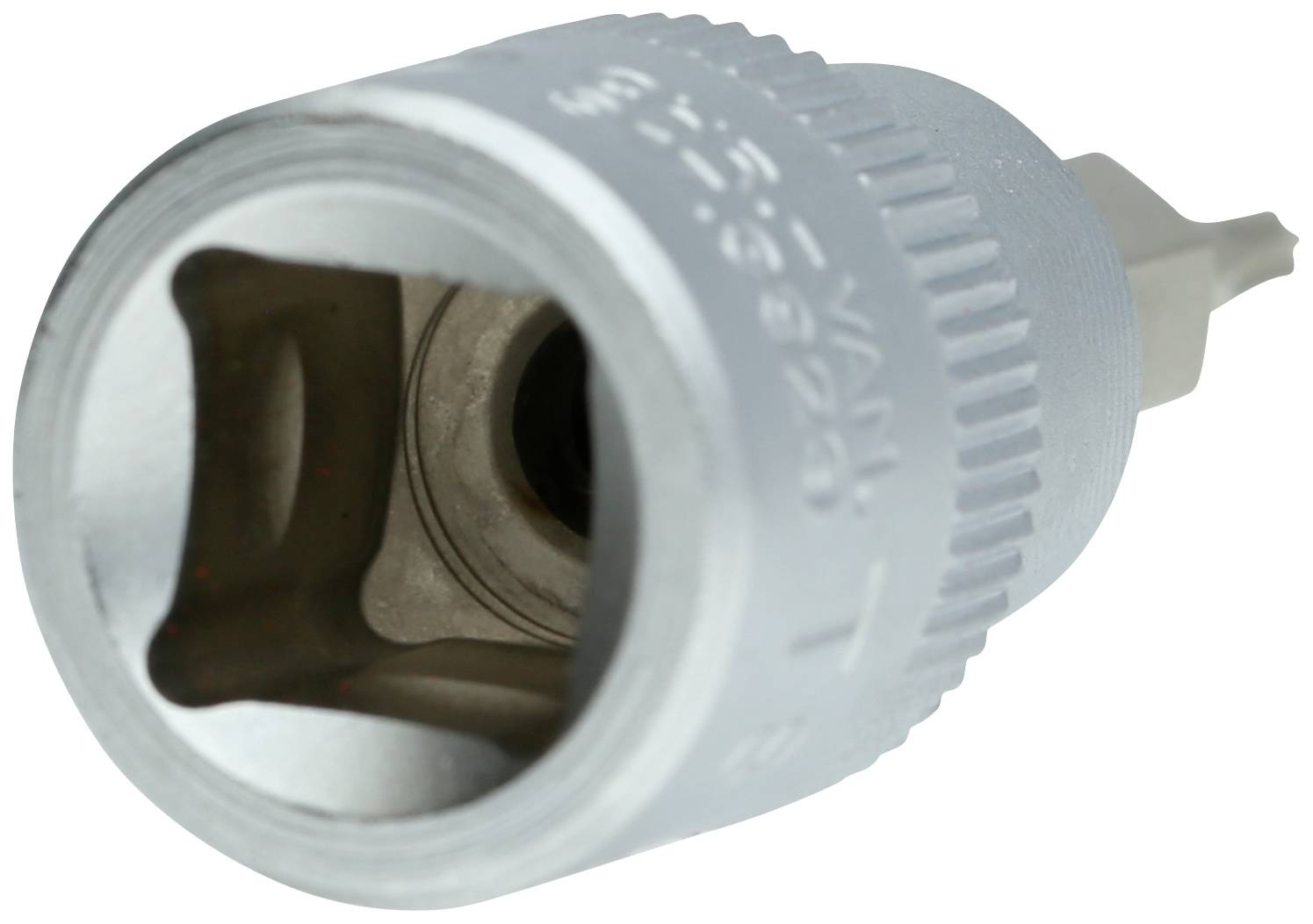 Zbliżenie srebrnego narzędzia z kwadratowym otworem i żebrowaną krawędzią, prawdopodobnie nasadka klucza nasadowego.