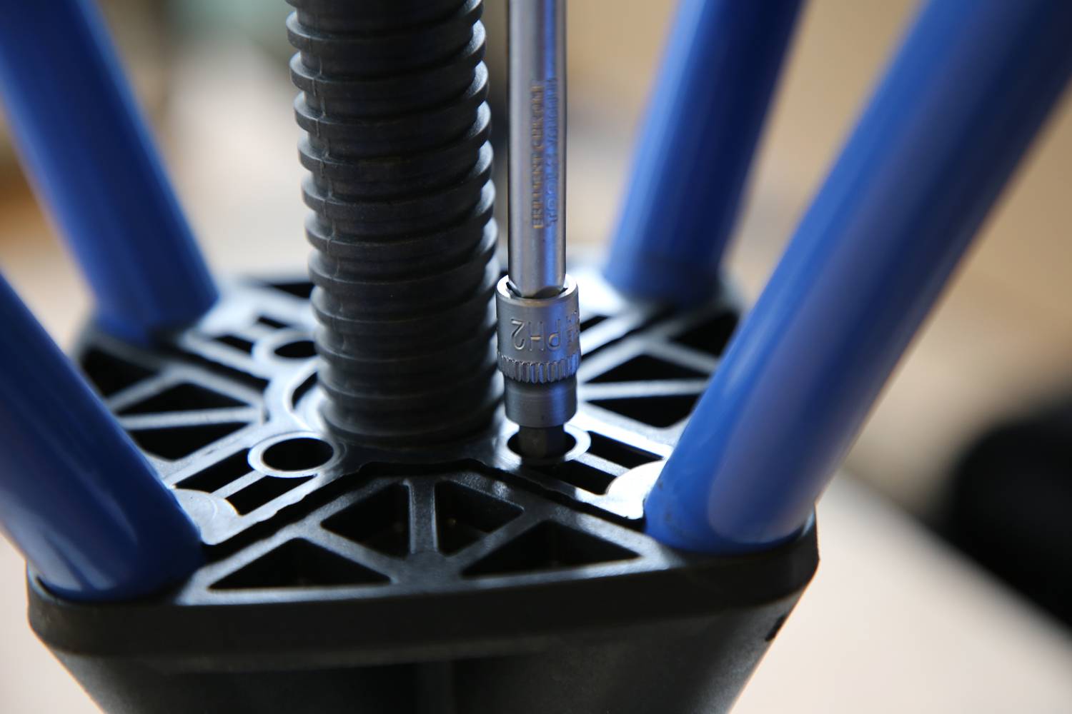 Zbliżenie metalowego narzędzia umieszczonego w czarnym, okrągłym elemencie z niebieskimi ramionami. Fokus na zastosowaniu narzędzia.