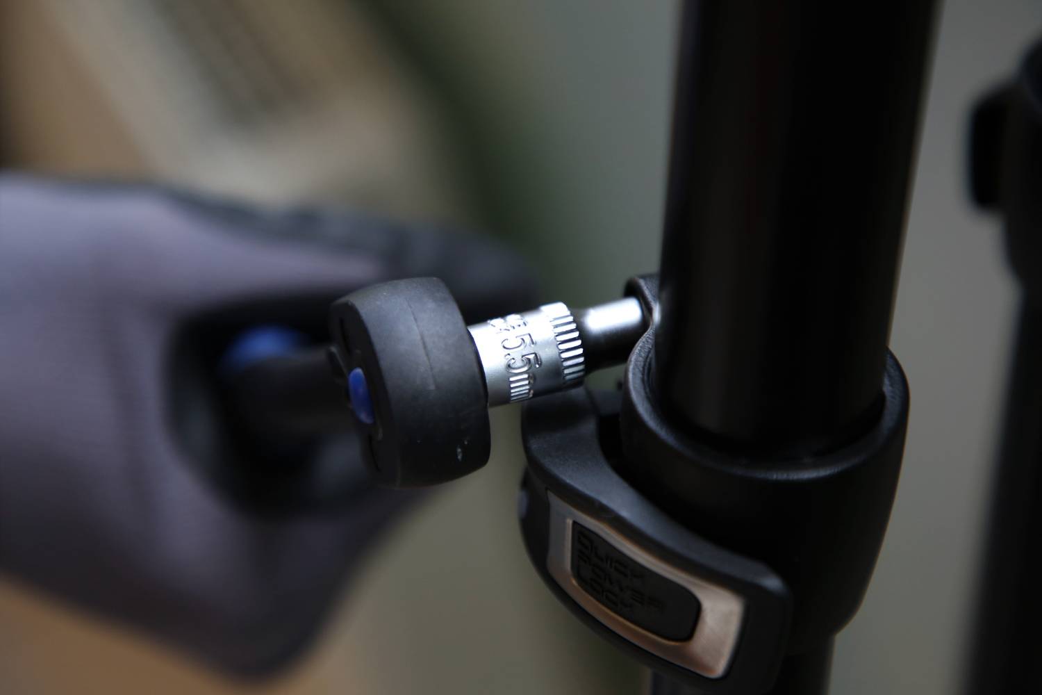 Dłoń w rękawicy obraca przy złączu statywu. Klucz płaski chwyta śrubę z oznaczeniem '5 mm'.