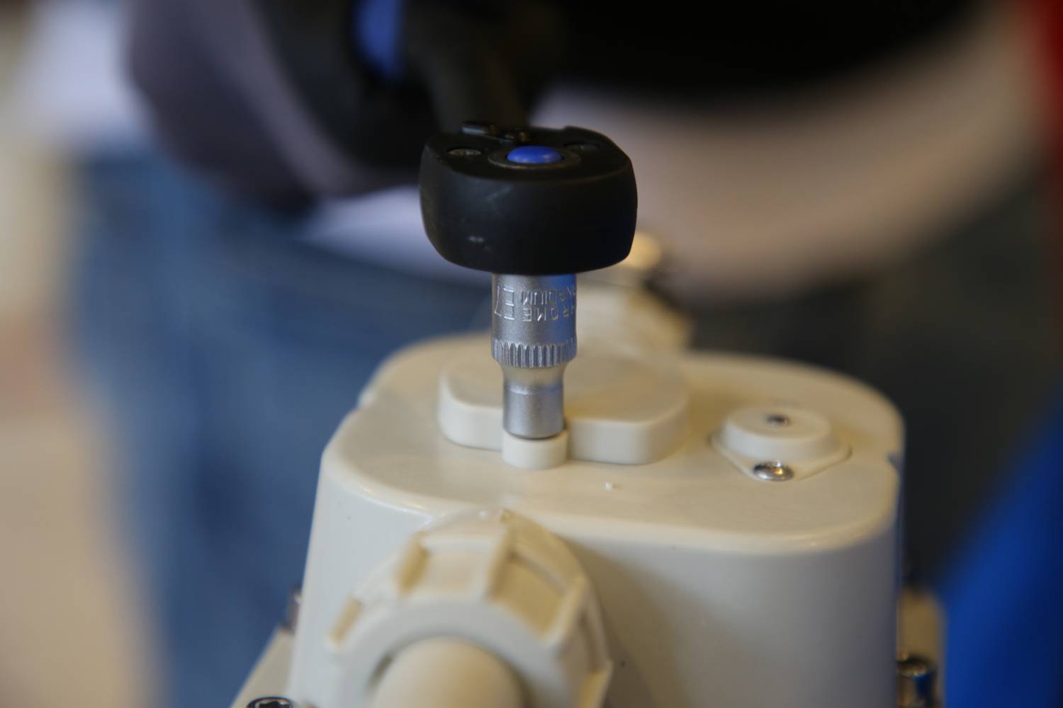 Zbliżenie klucza dynamometrycznego ustawianego na śrubie urządzenia mechanicznego. Fokus na precyzji i technice.