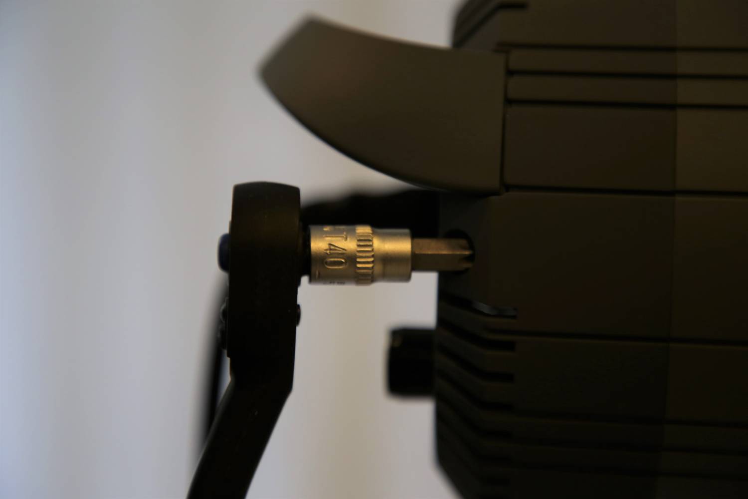 Czarne urządzenie z podłączonym kablem, przytrzymywane metalową śrubą z napisem 'AL 10'.