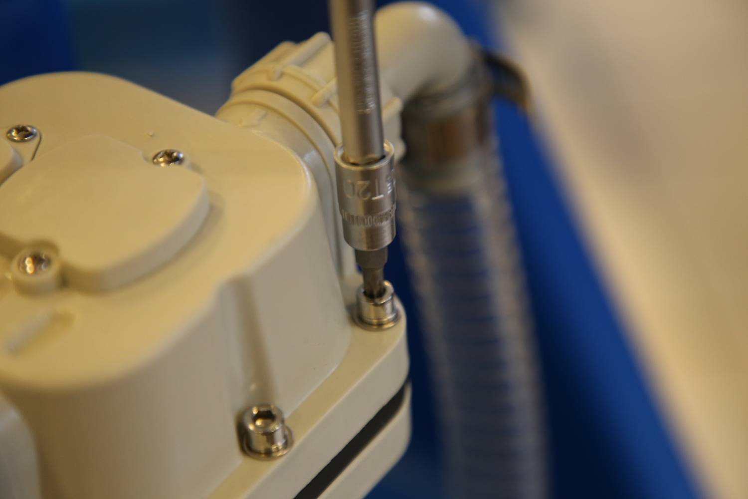 Zbliżenie narzędzia wkręcającego śrubę w urządzenie techniczne, ze szczegółowym ujęciem mechanizmu i materiału.