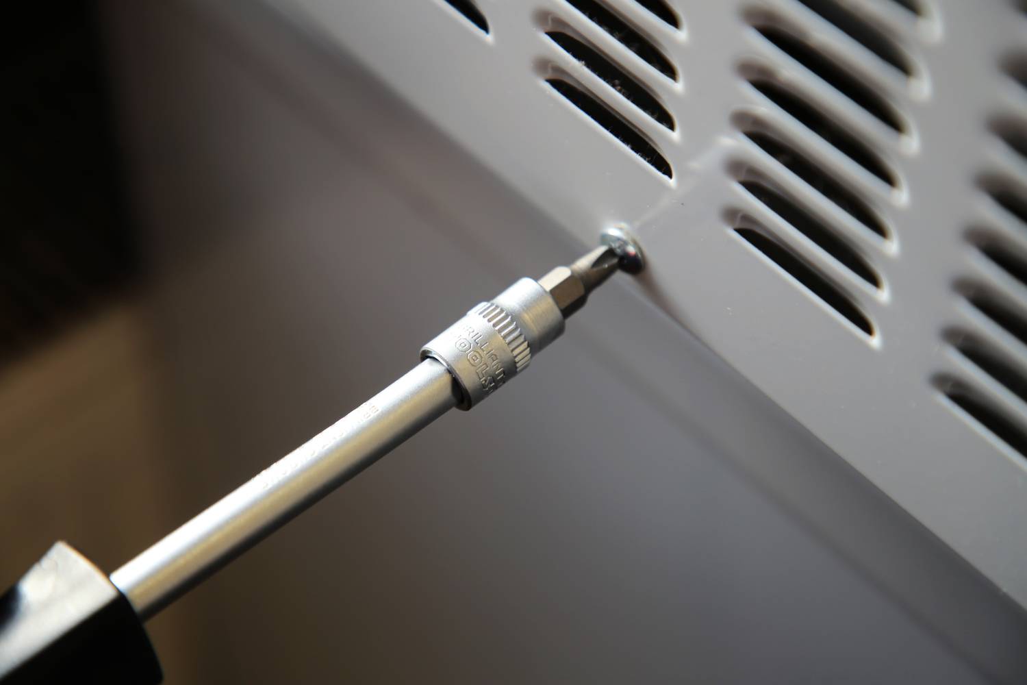 Śrubokręt jest używany do dokręcenia śruby w metalowej kratce.