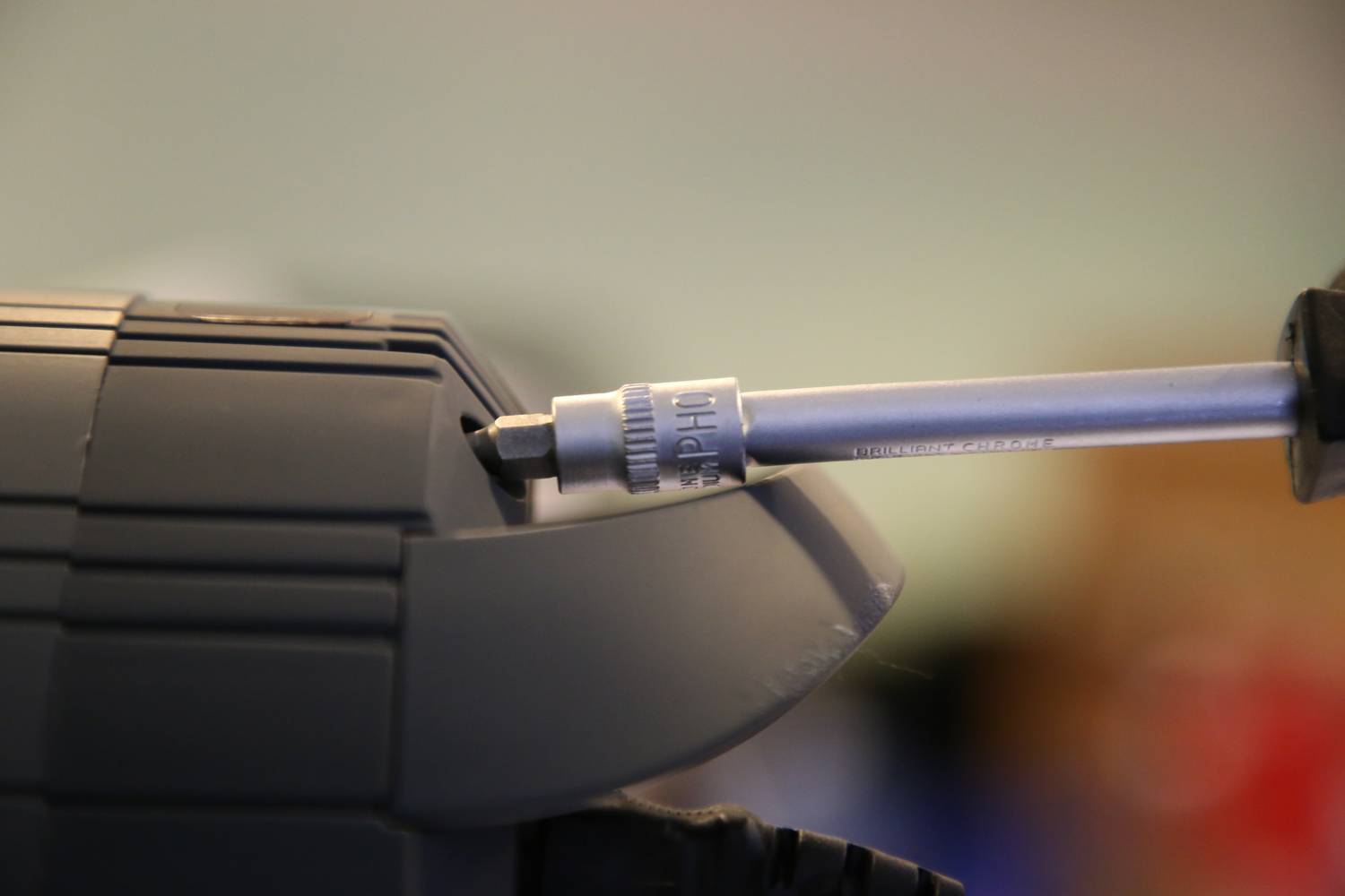 Zbliżenie osoby wkręcającej śrubę wkrętakiem. Tło jest rozmyte.